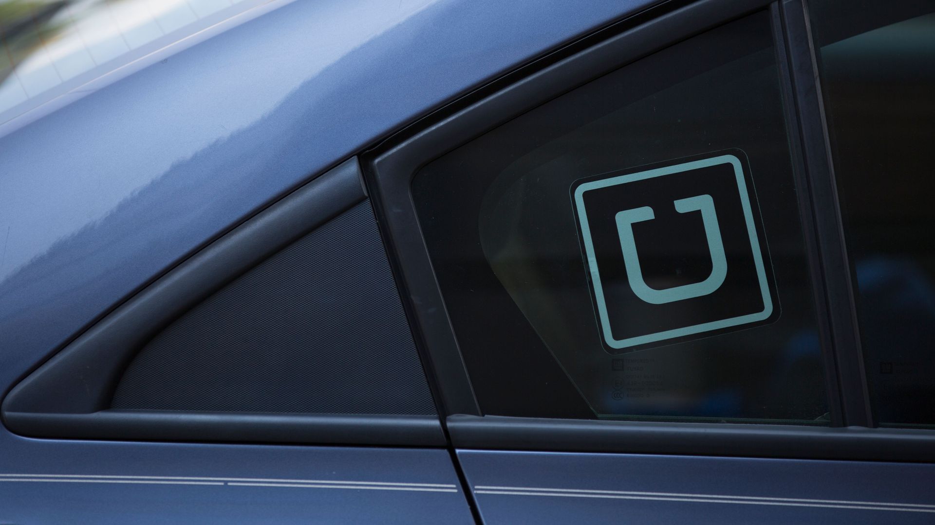 A car with an Uber sticker in the rear passenger window