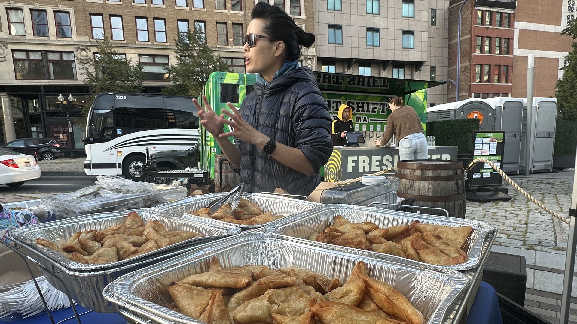 Chef Tracy Chang gesticulates behind the table to a customer (out of view), standing over trays of sambus (also known as sambusas or samosas in some cultures) one afternoon.