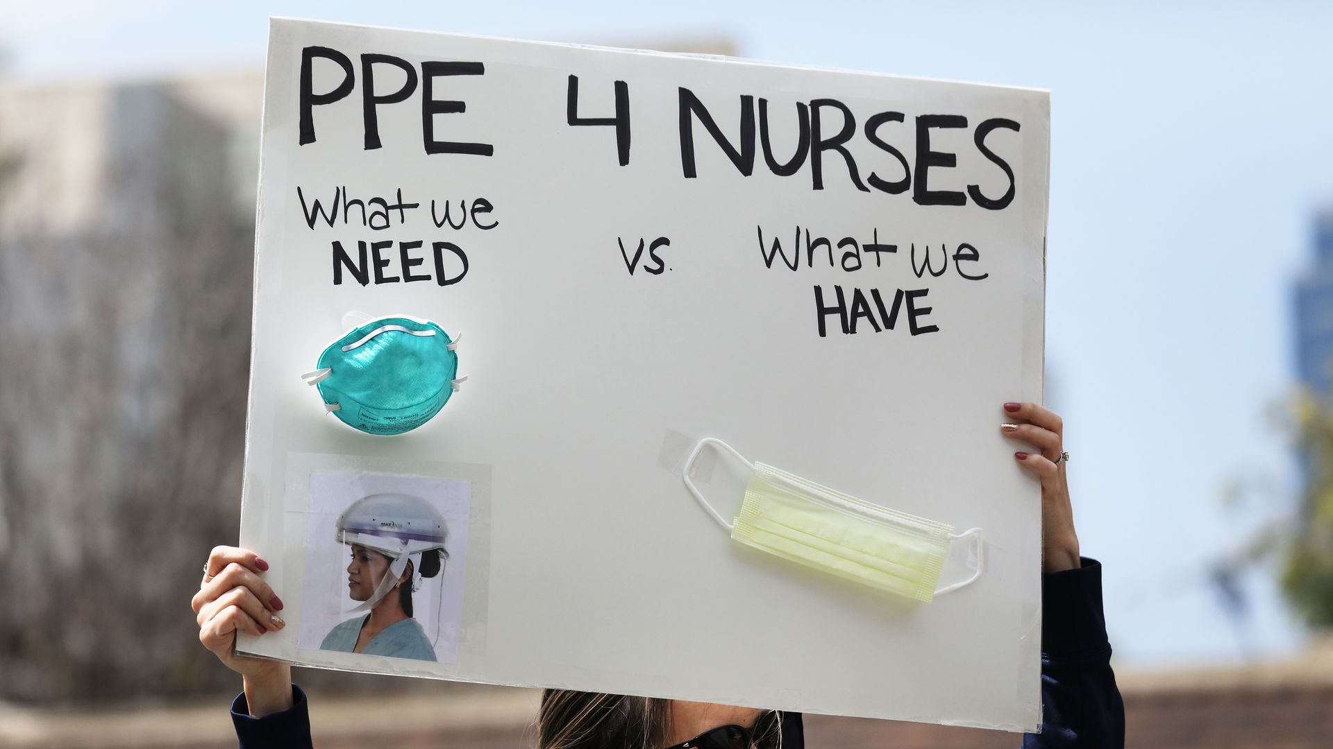 A nurse holds up a sign to protest the lack of personal protective gear available