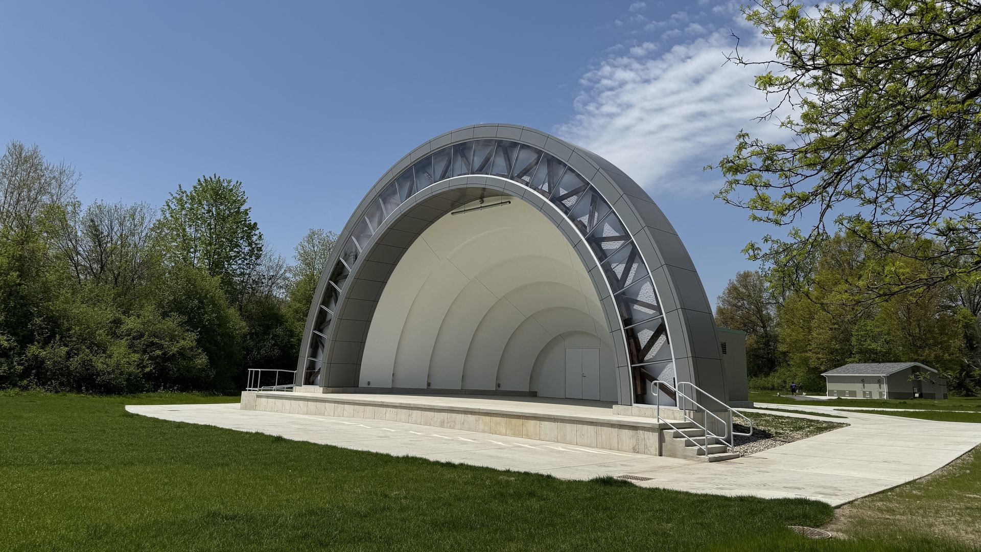 A stage set against a grassy lawn. The stage is covered in a half circle ceiling that gives a tunnel effect