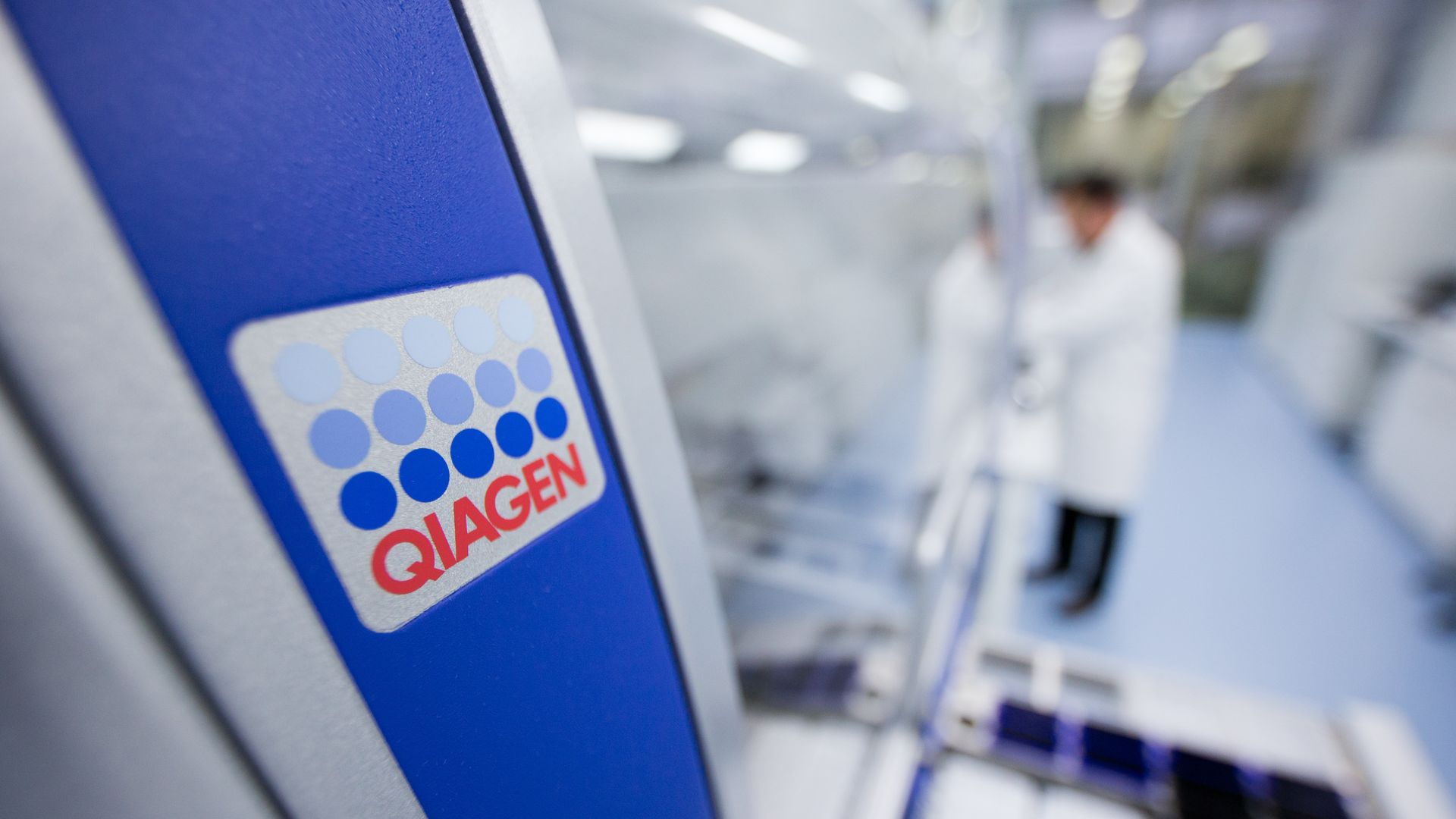 The red, white and blue Qiagen logo on a machine in a factory.