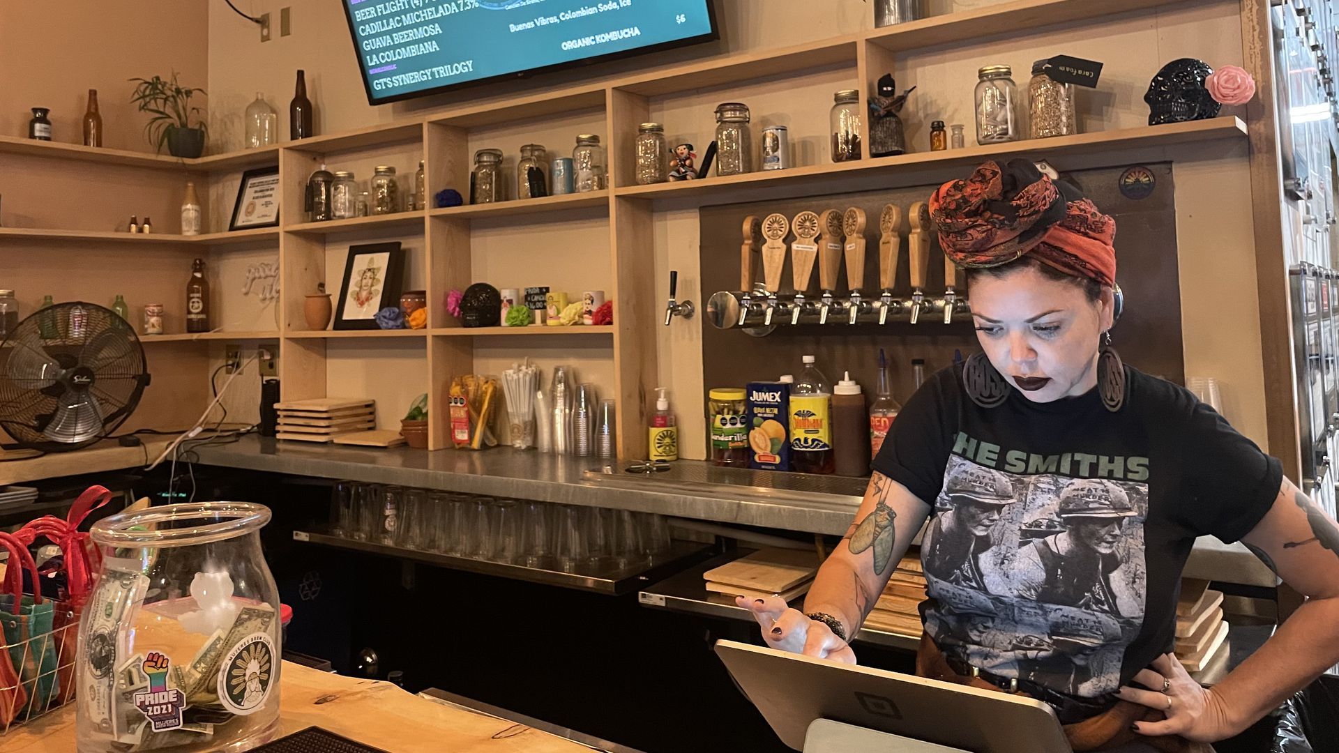 A server at Mujeres Brew House in San Diego rings up a customer in front of a selection of craft beers.