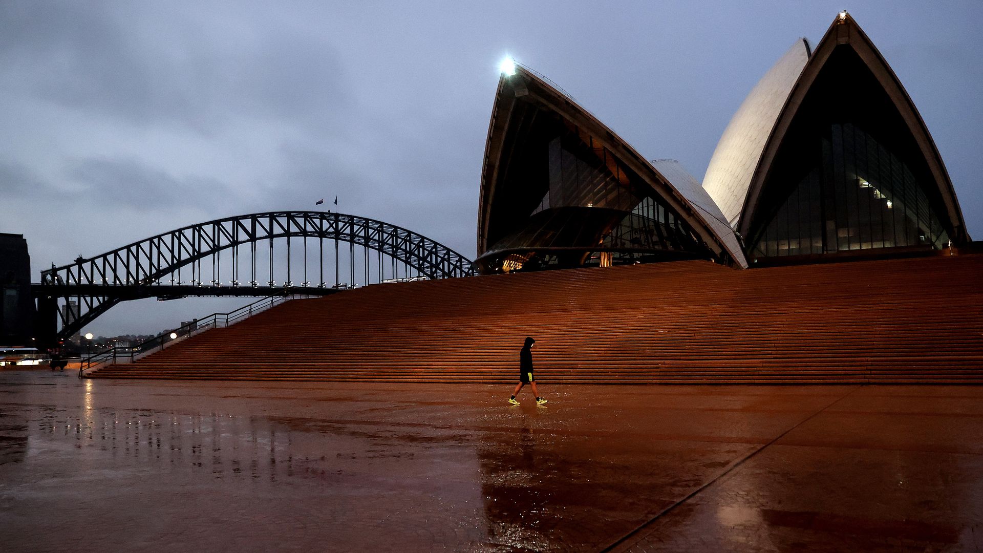 A pedestrian walks along the near deserted Sydney Opera House.