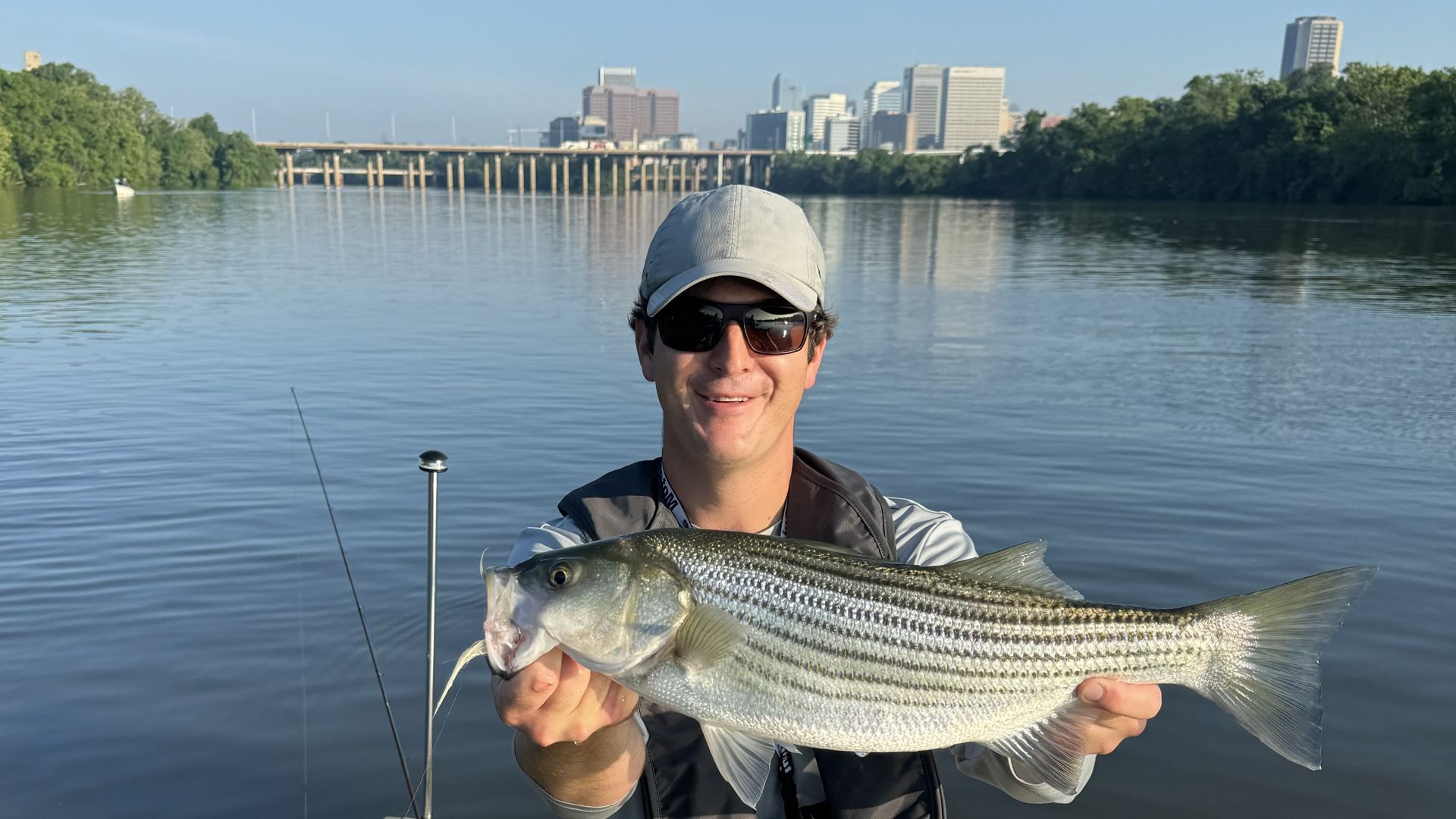 A man with a big fish standing in front of the city skyline
