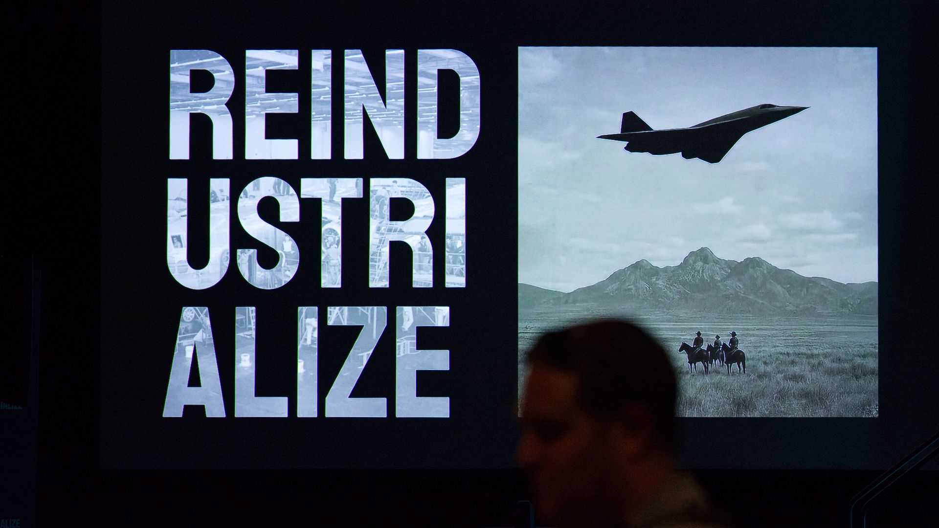 A person passes by a large electronic screen. The room is dark, with the only light coming from the screen.