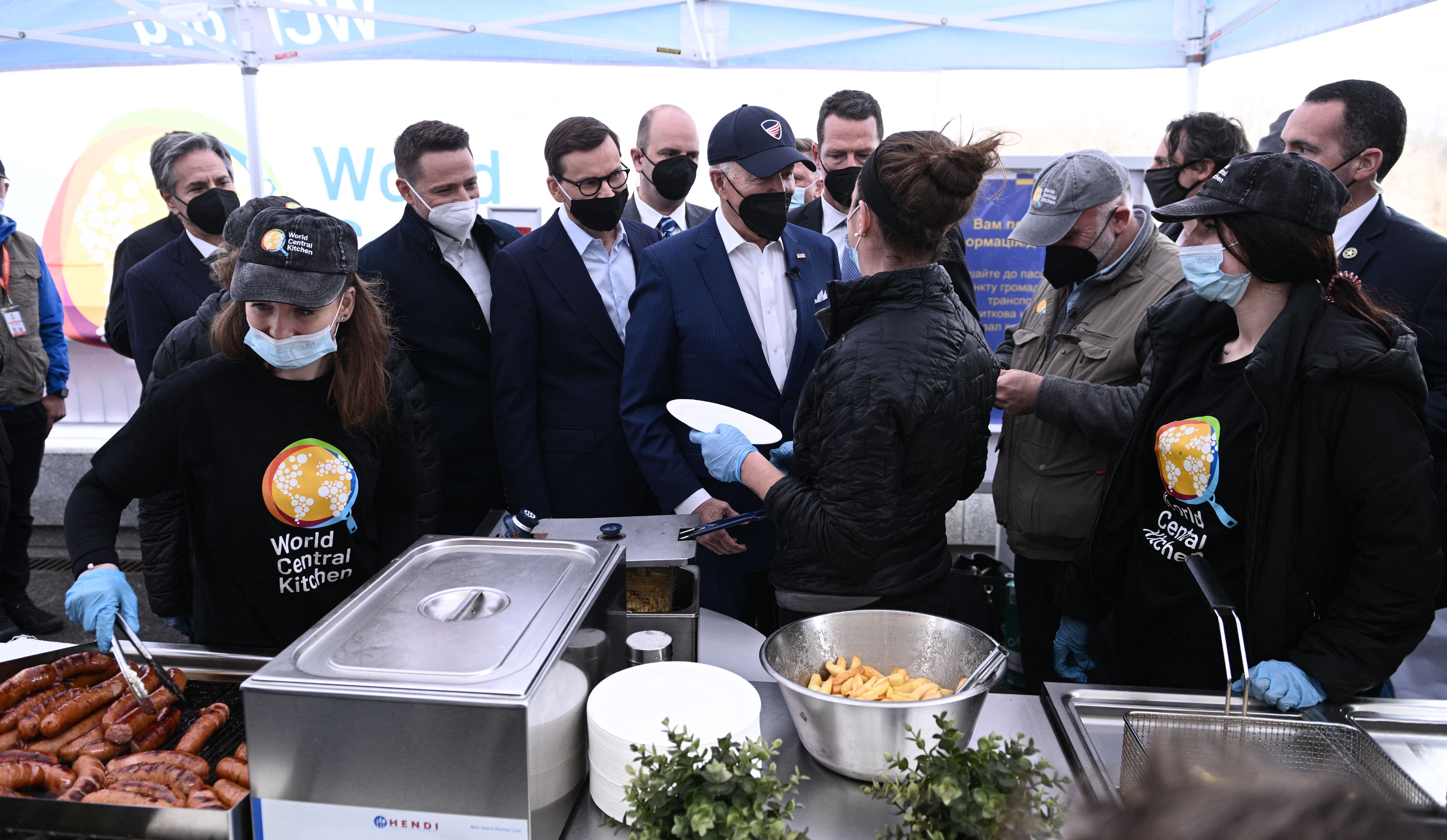 US President Joe Biden (C) and Polish Prime Minister Mateusz Morawiecki (4L) greet chefs during a tour of a soup kitchen by nonprofit organization World Central Kitchen