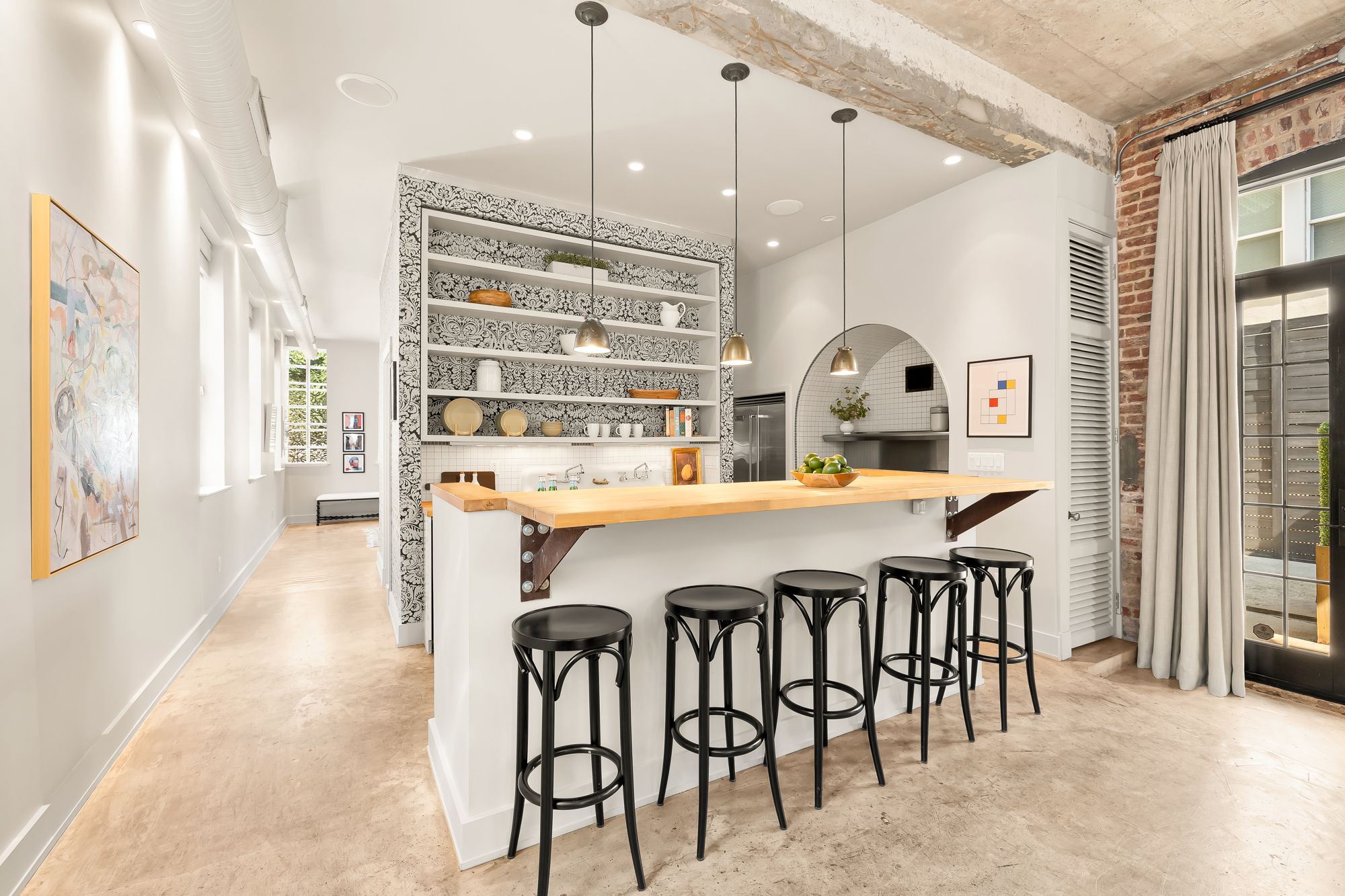 A white kitchen with a counter and black stools.