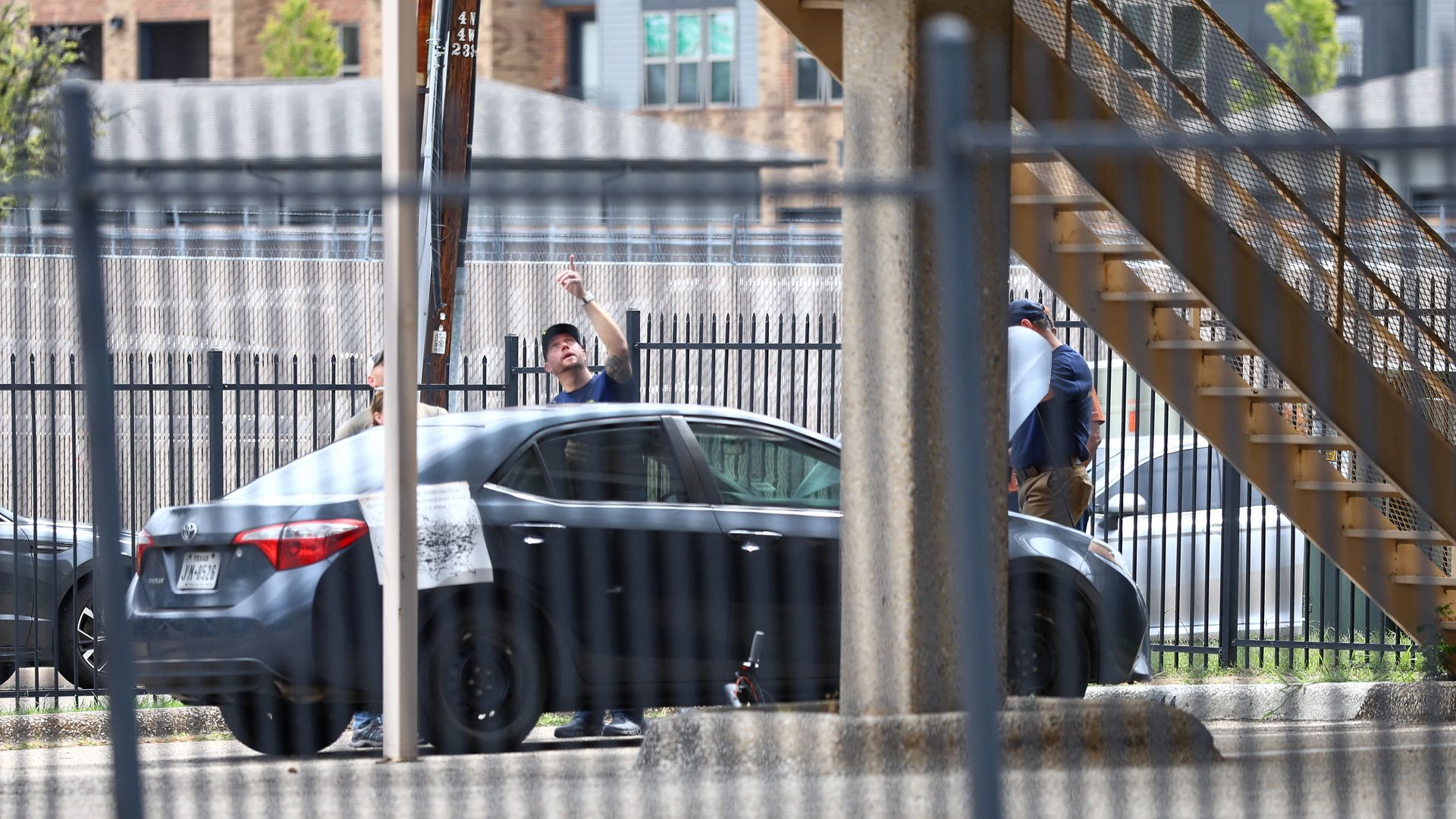 Law enforcement, including members of the FBI, investigate a vehicle parked near a building in Dallas.