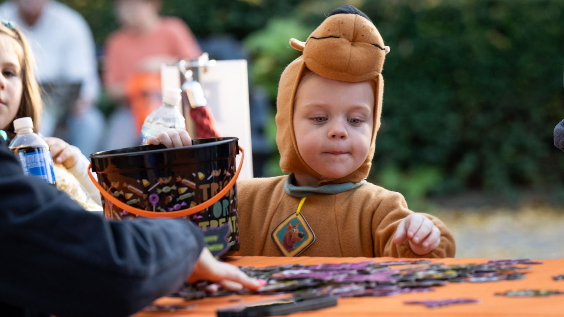 A boy in a Scooby Doo costume grabs trick-or-treat candy from a table