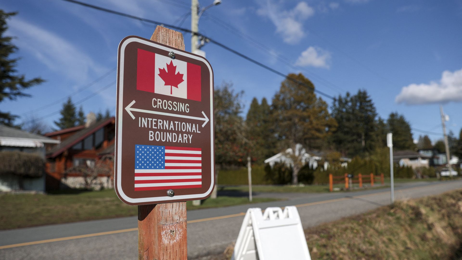 A sign marks the border between the U.S. and Canada, reading "CROSSING INTERNATIONAL BOUNDARY"  and featuring the countries' flags.