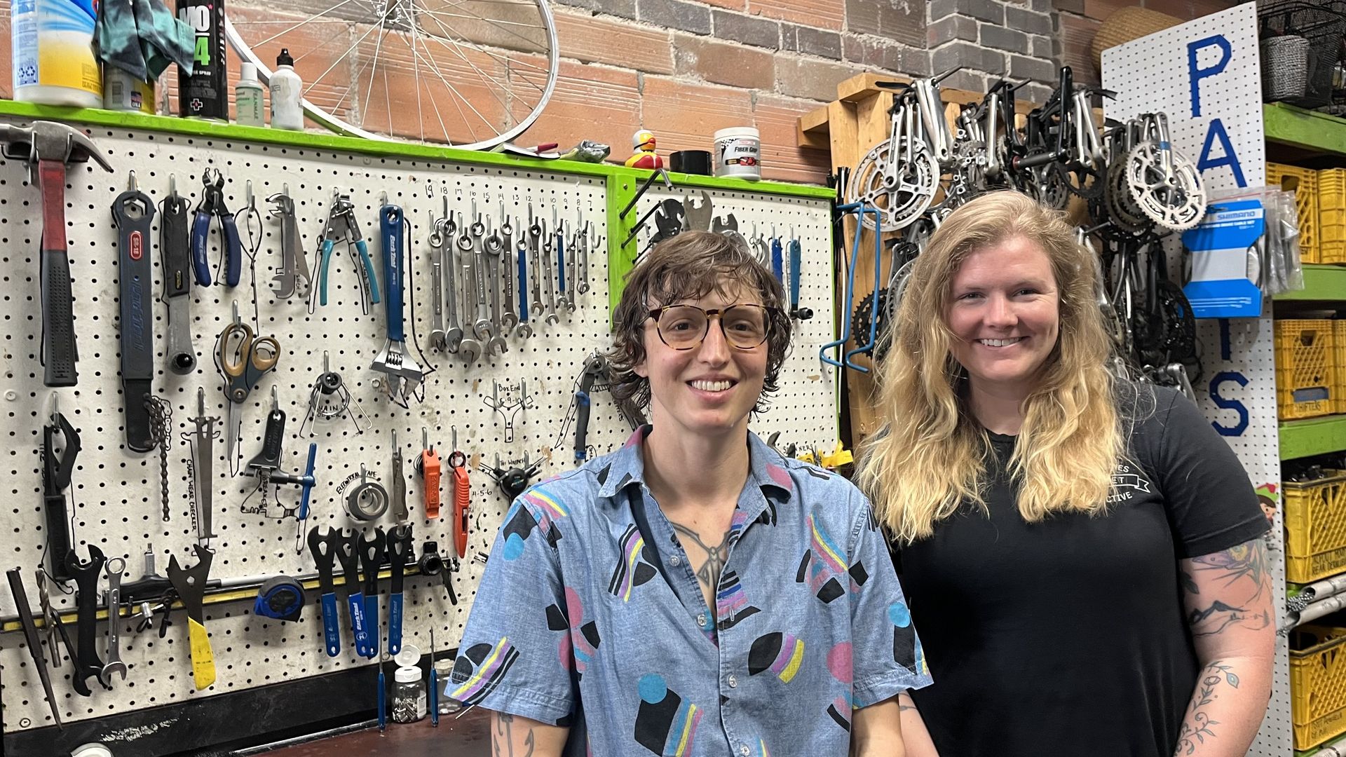 Two people standing in front of a bike work station