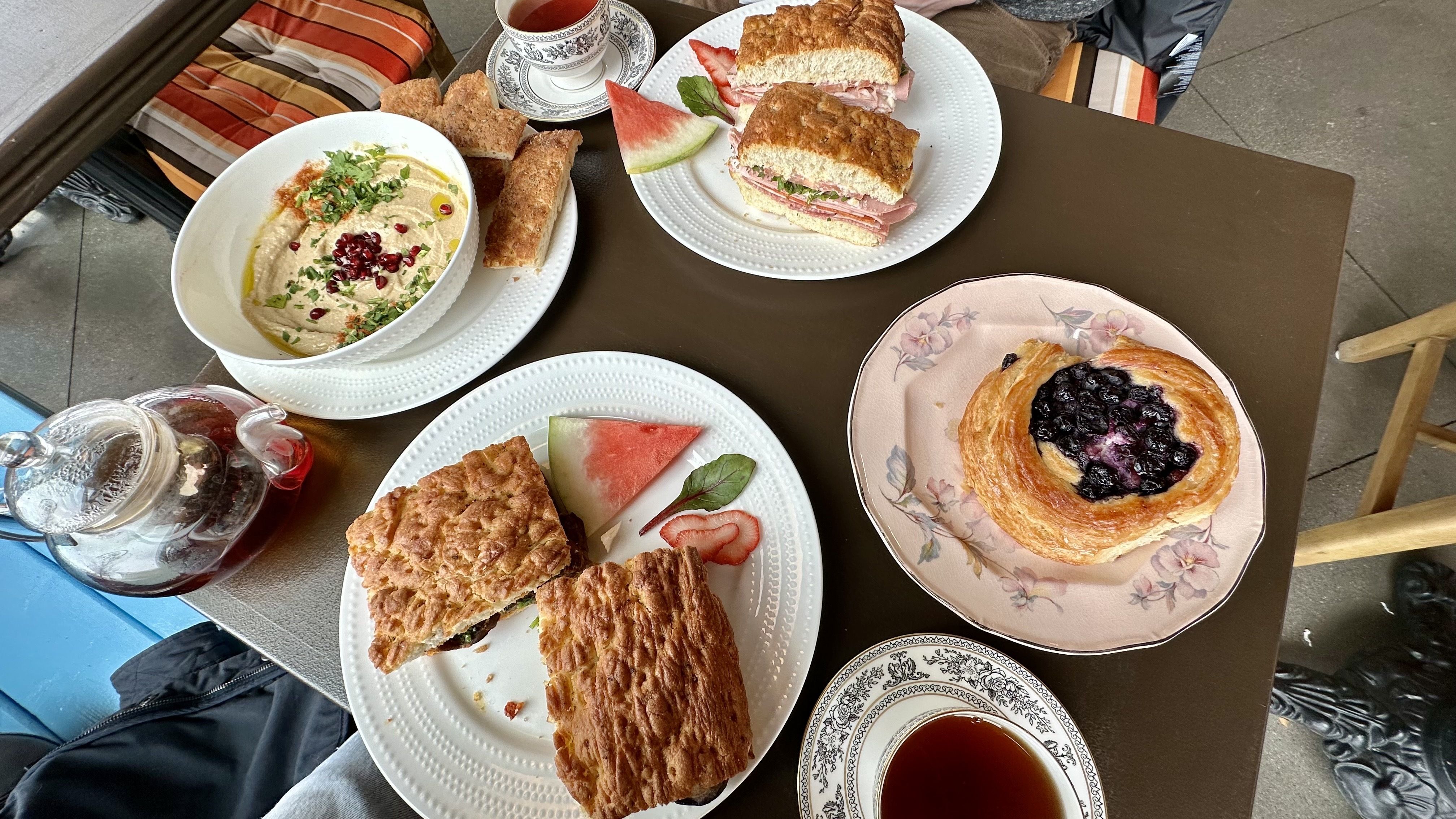A photo of plates of sandwiches, pastries, hummus and cups of tea on a table at Urban Cafe.
