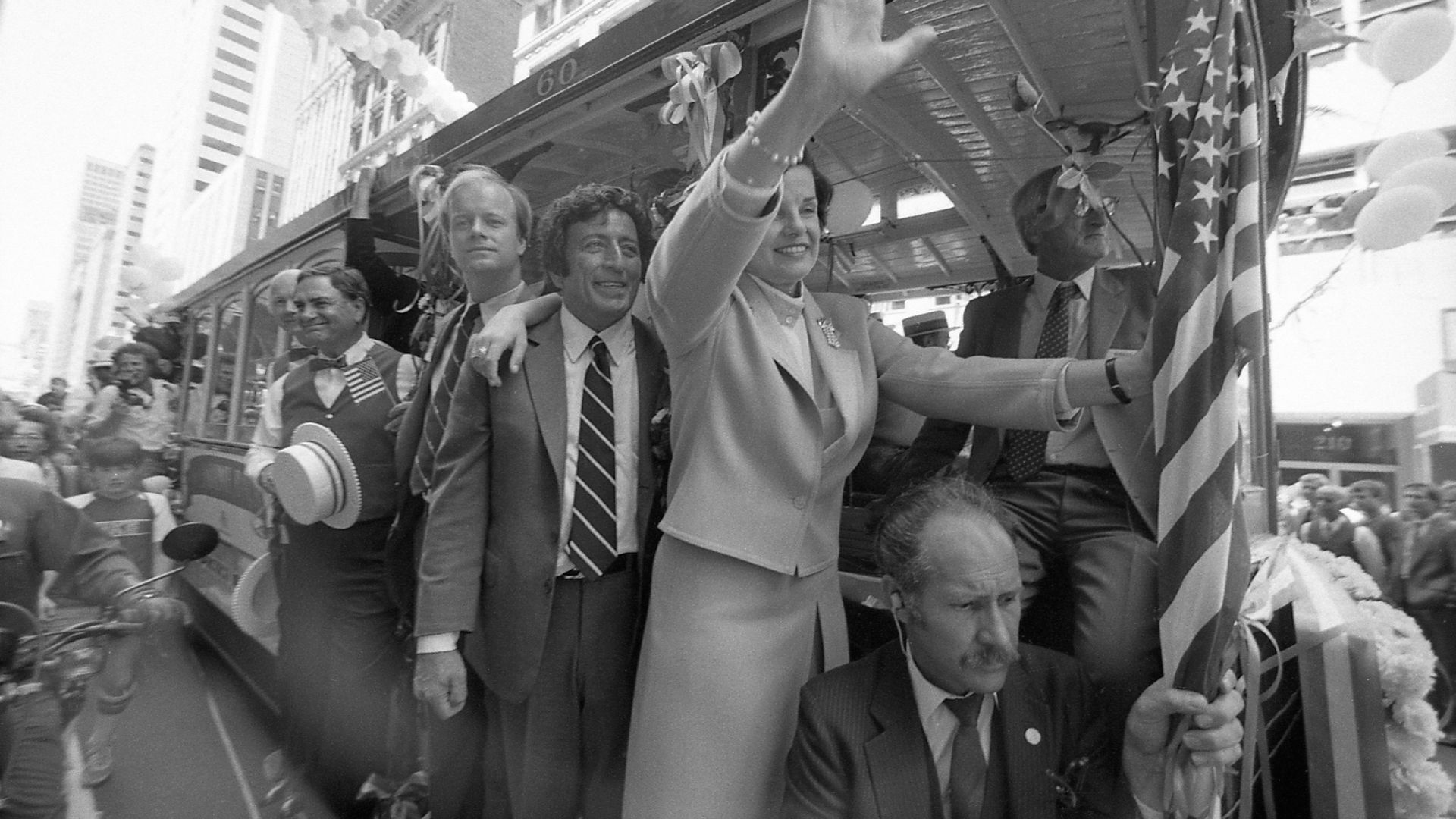 Black-and-white photo of Tony Bennett riding a cable car in San Francisco with Dianne Feinstein