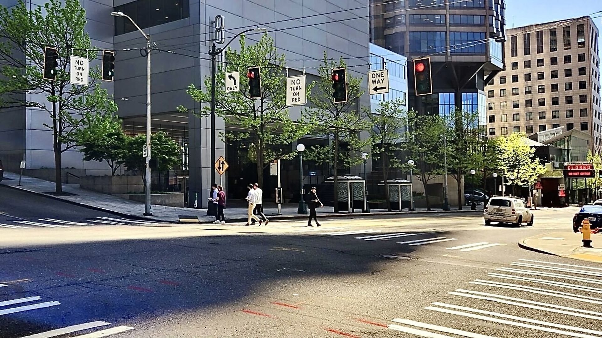 An intersection with crosswalks at multiple signs that say "No turn on red," with downtown buildings in background. 