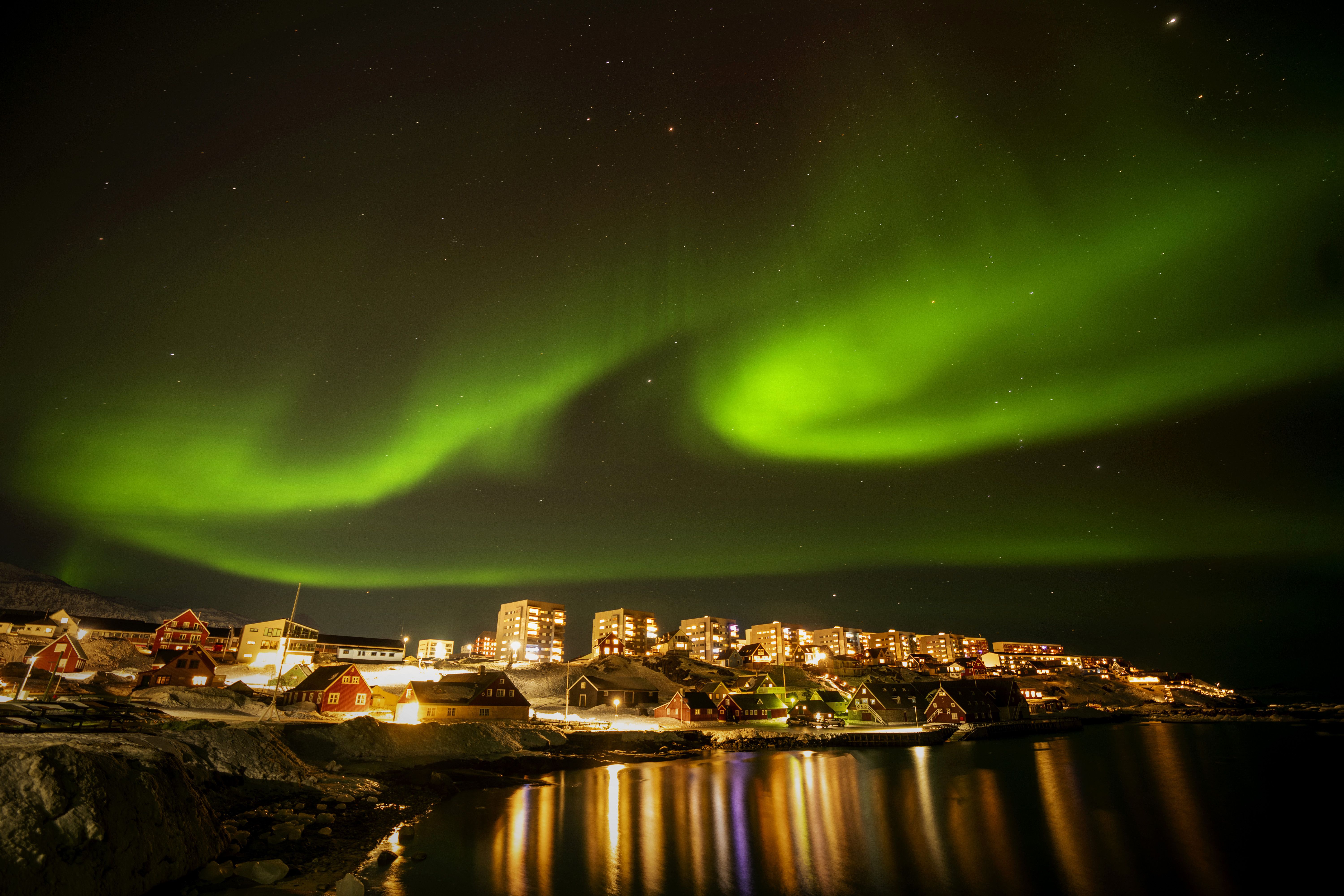 The northern lights appear over homes in Nuuk, Greenland, Monday, Feb. 17, 2025. (AP Photo/Emilio Morenatti)