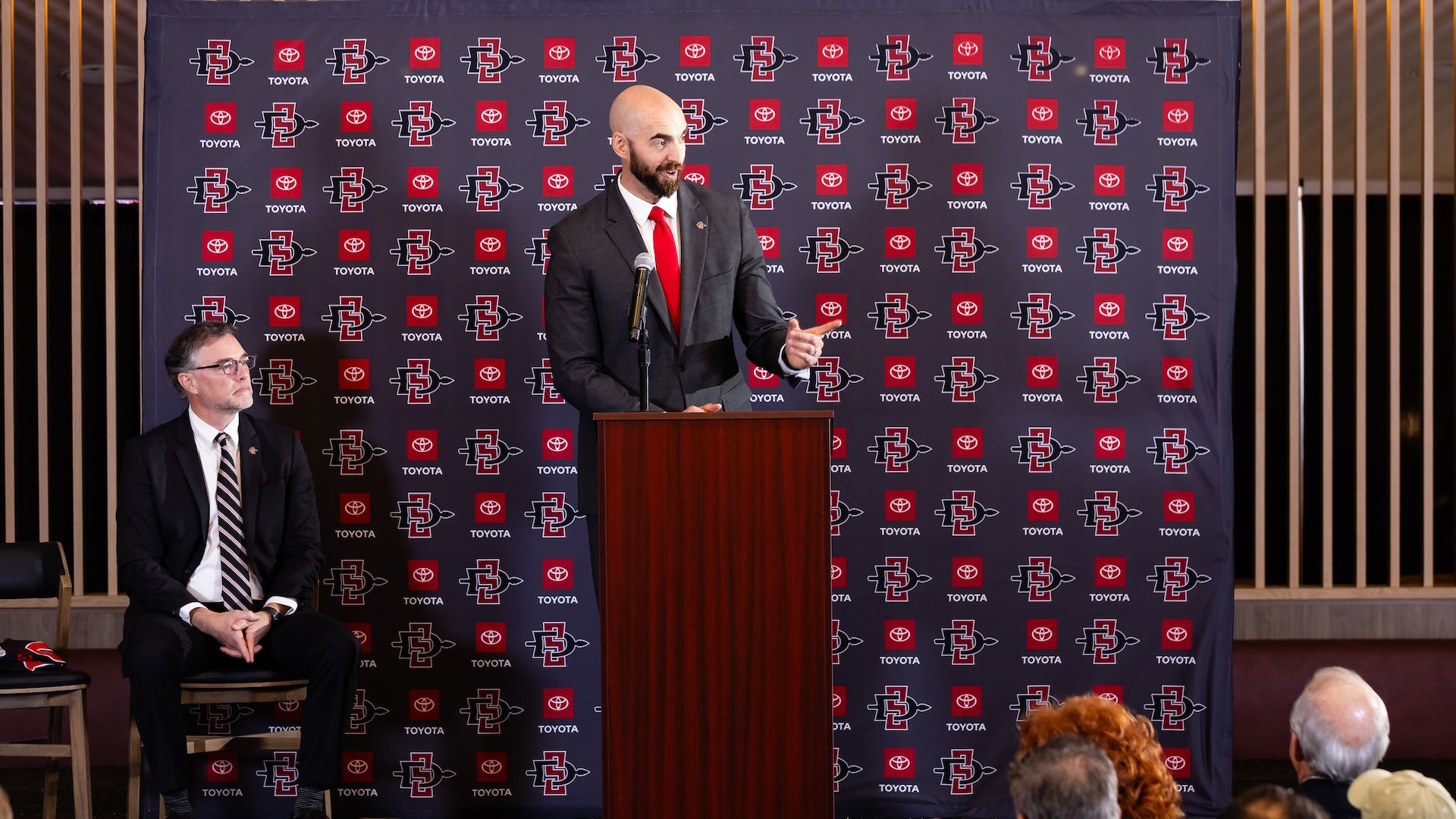 San Diego State head football coach Sean Lewis stands at a podium.