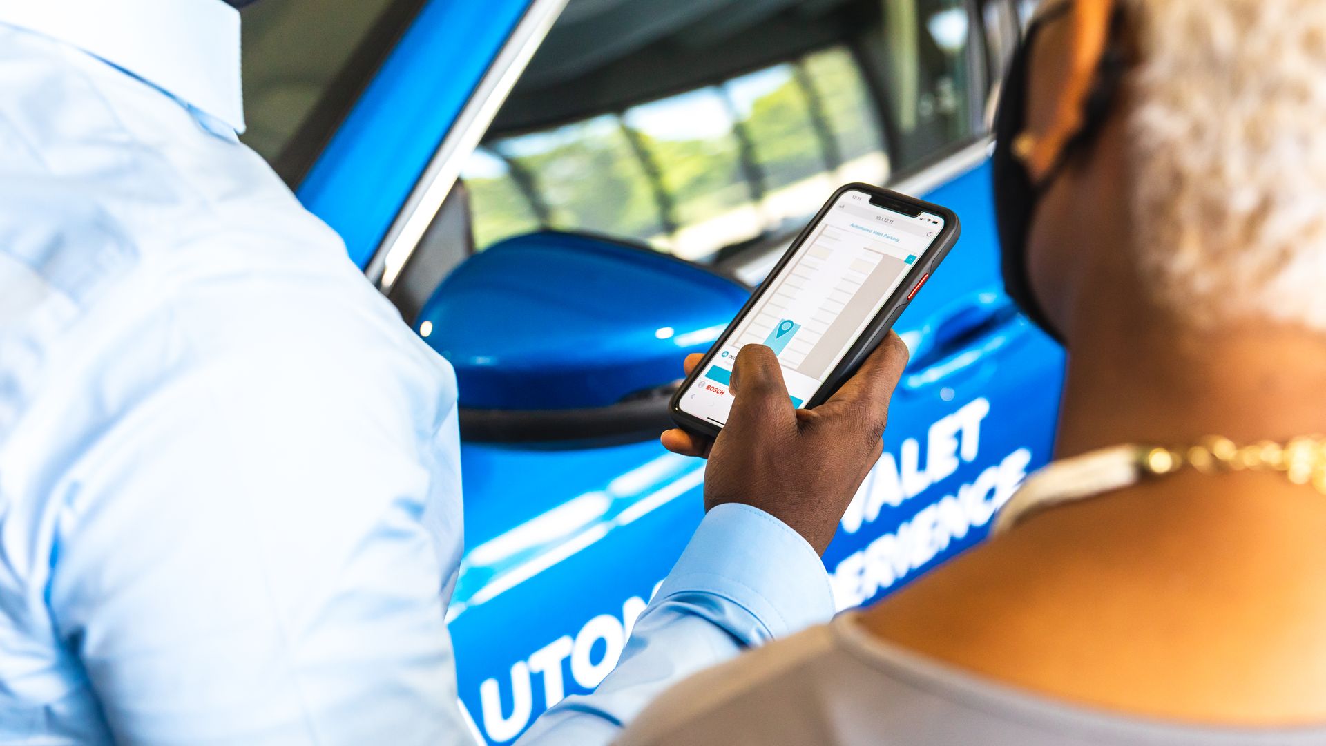 Image of motorist using smartphone to automatically park his car
