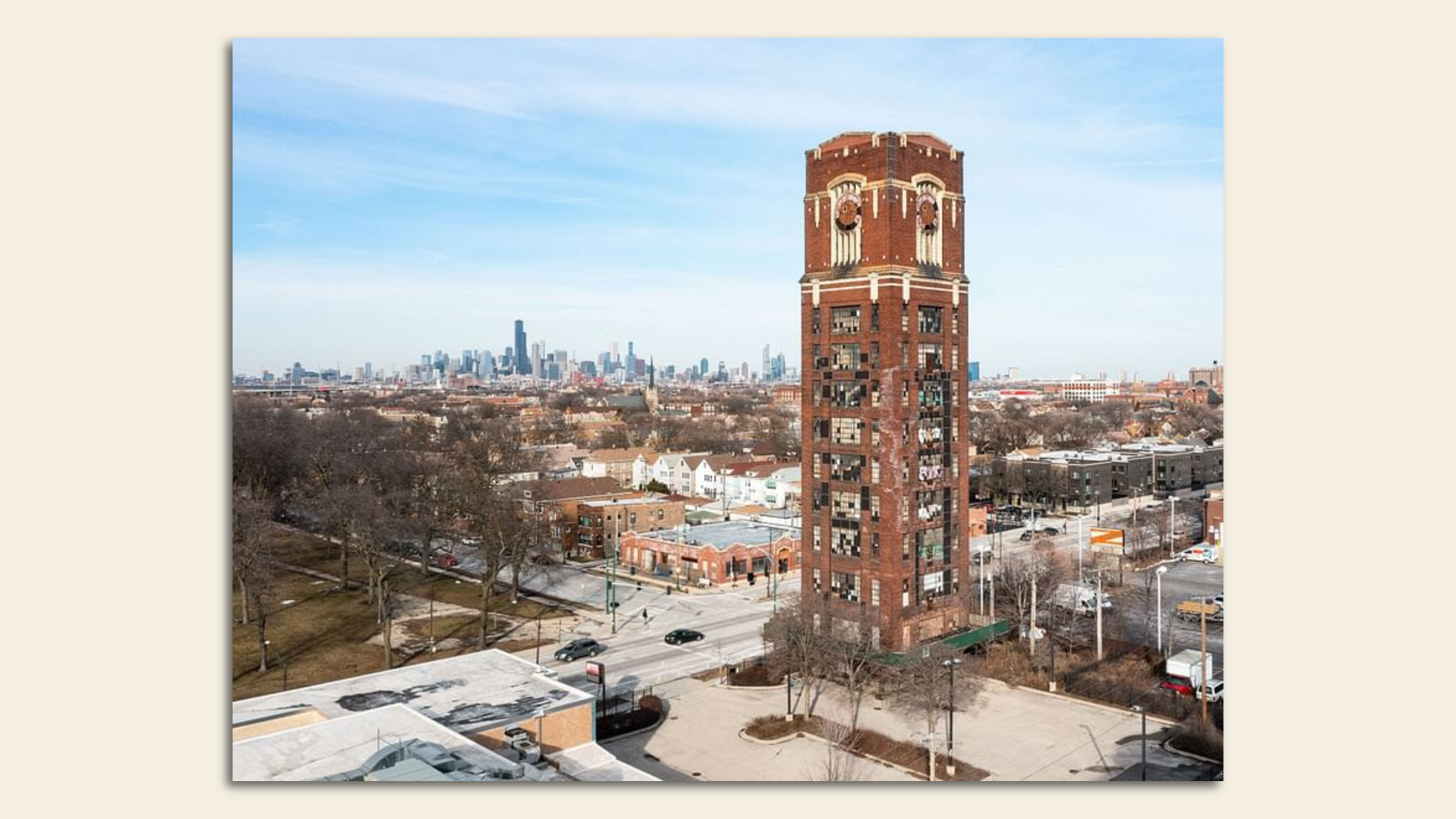 Red brick clock tower with the skyline of Chicago in the background.
