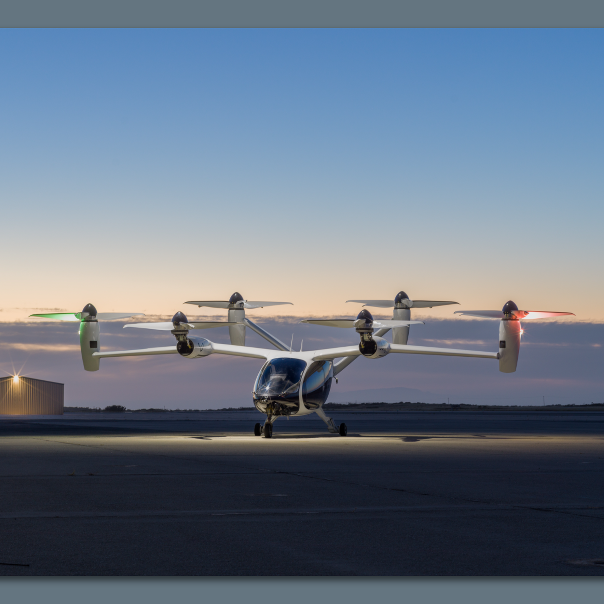 Image of Joby's multi-rotor electric vertical takeoff and landing aircraft on an airfield at dusk. 