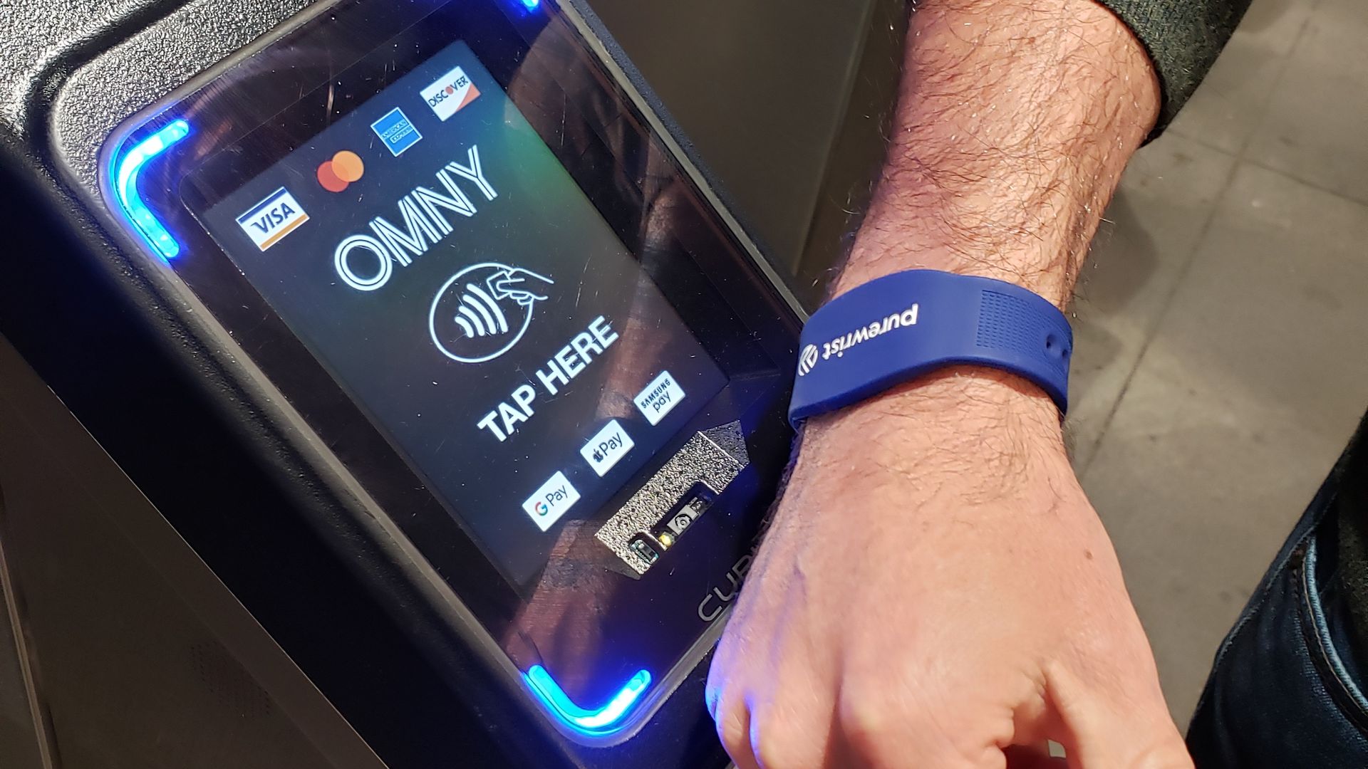 A subway rider swipes a payment bracelet against a NYC subway payment terminal.