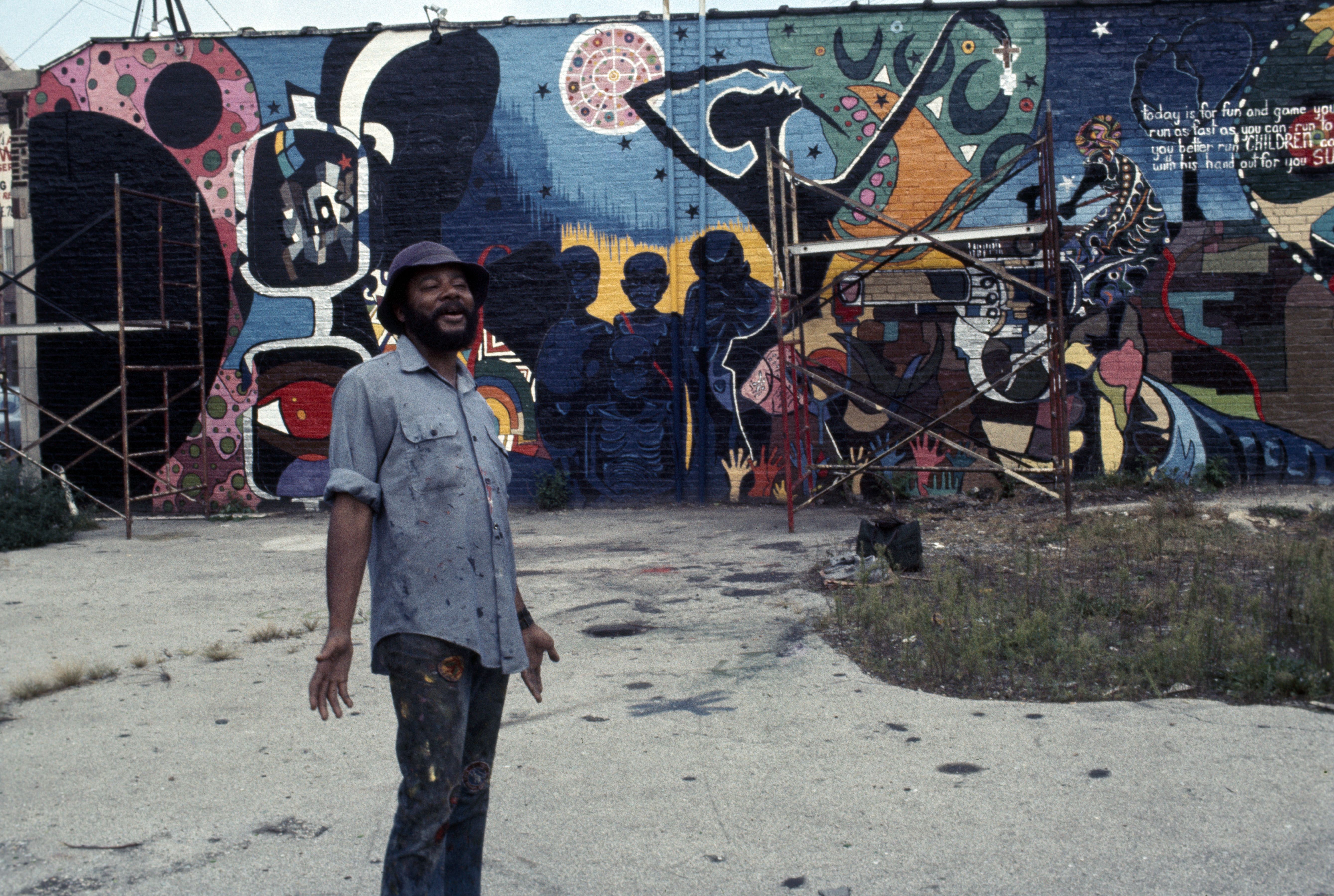 Photo of a man standing in front of a mural 