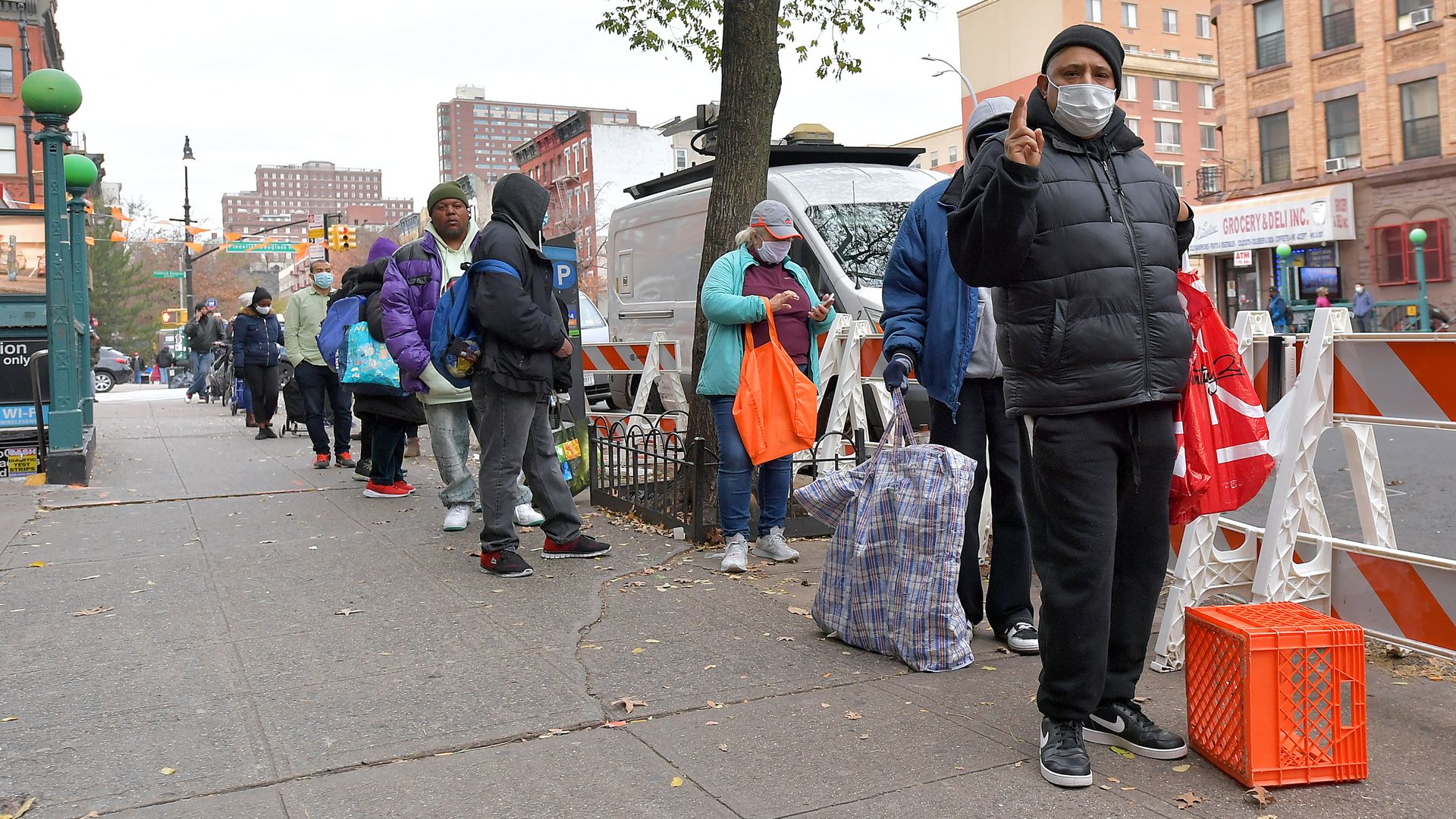 People wearing winter coats and face masks stand in a line outside