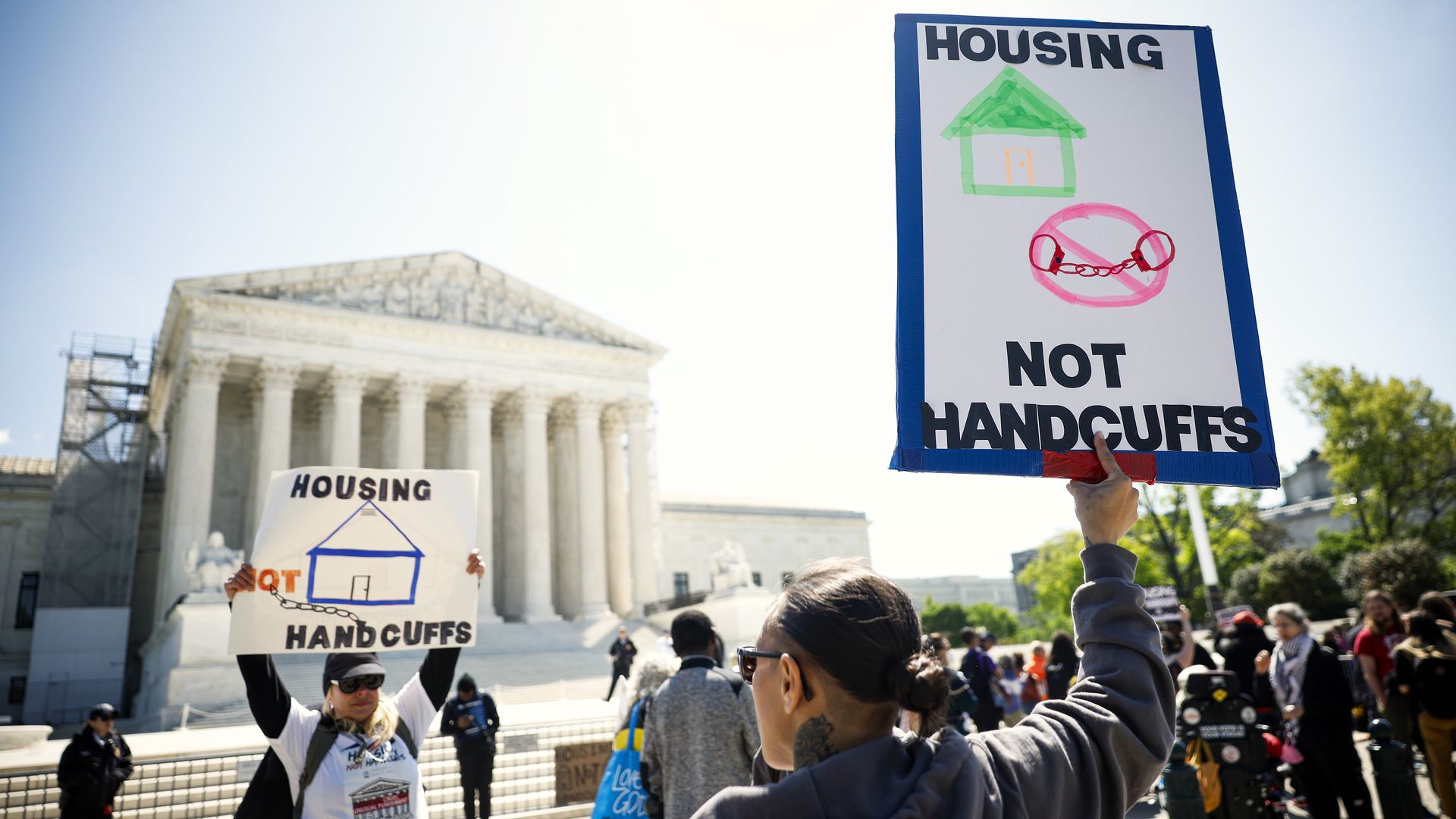 People hold signs in front of the US Supreme Court building.