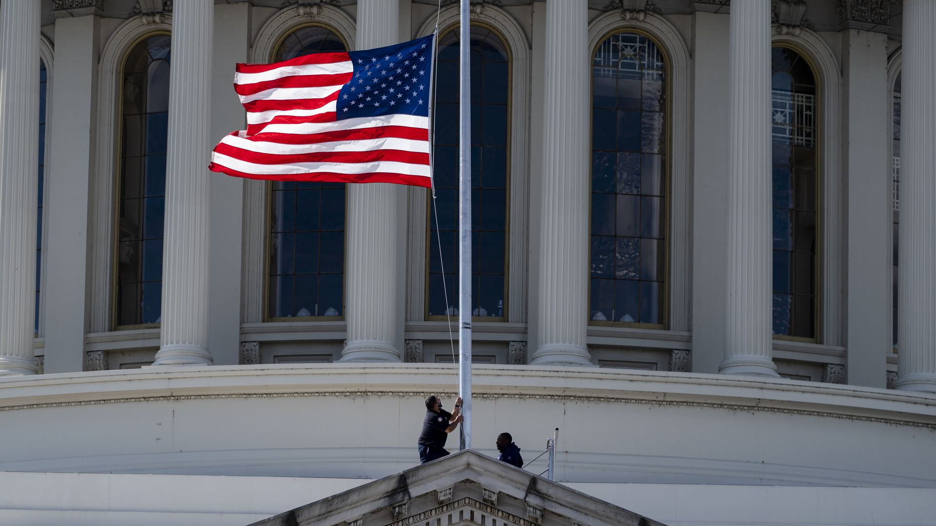 Workers are seen lowering a flag at the U.S. Capitol to honor Colin Powell.
