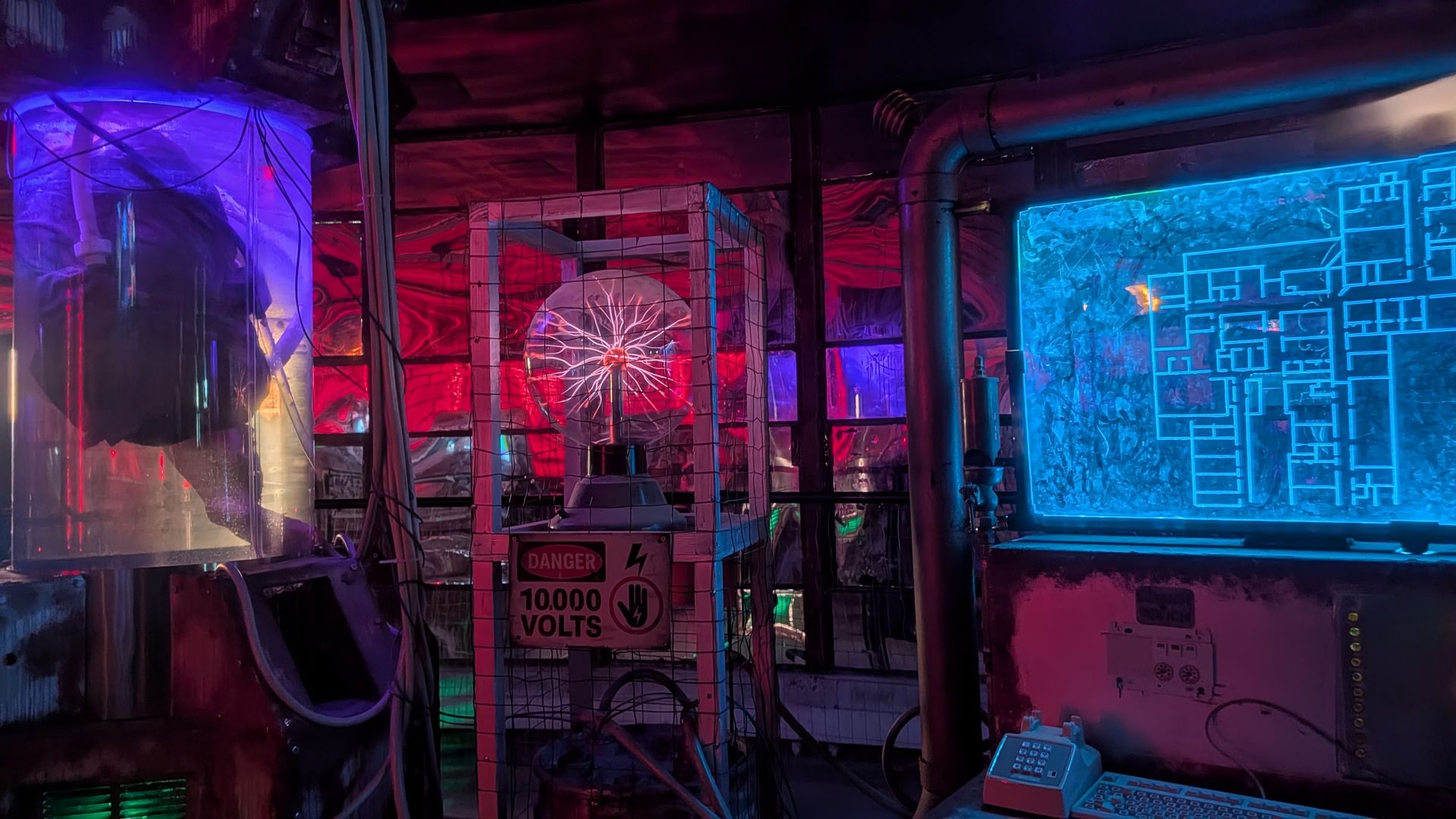 Futuristic lab with red and blue neon. A glass cage houses a glowing circular plasma device with branching filaments. To the right, a blue holographic grid panel; foreground shows a 10,000-volt danger sign and a keyboard.