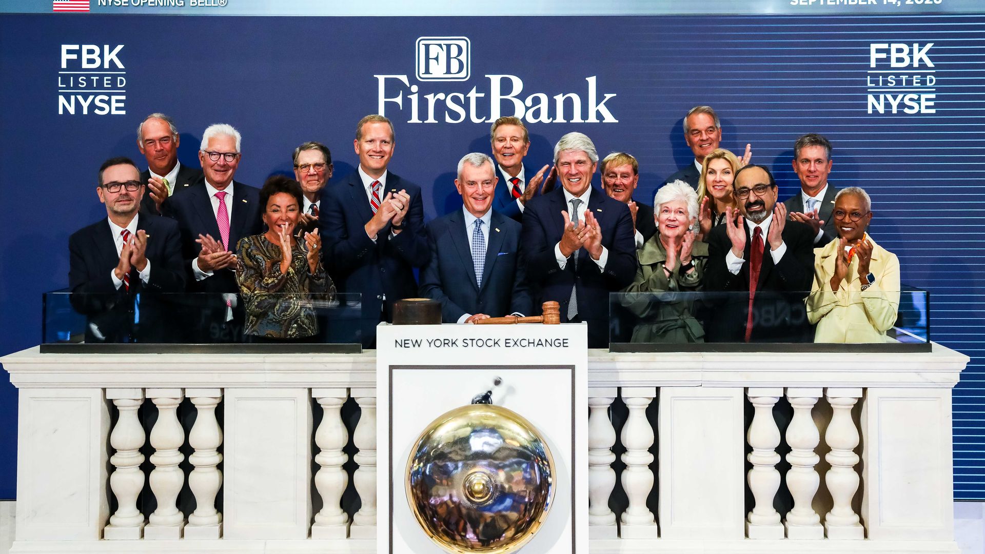 Executives applaud at the NYSE opening bell ceremony for FirstBank (FBK) on a blue backdrop with the FirstBank logo, NYSE banners, and the date September 14, 2026.