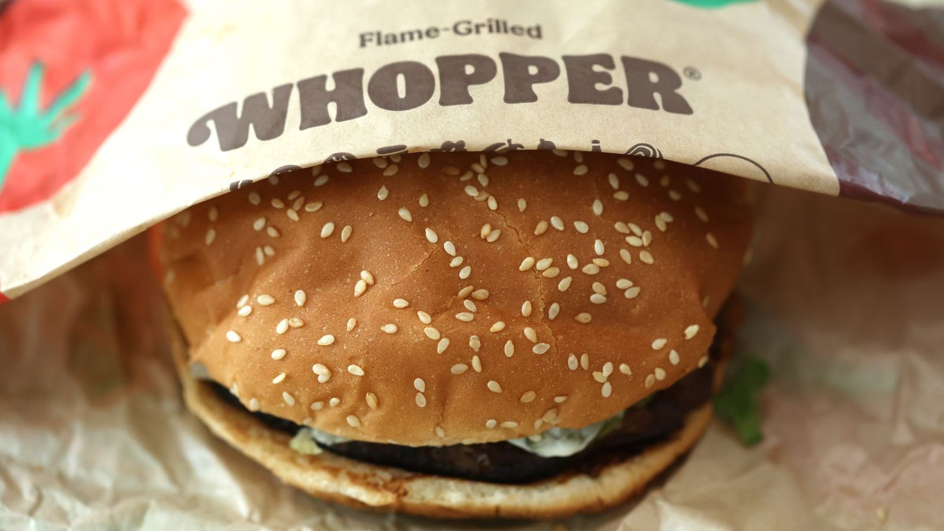 Burger slightly covered with wrapper that says Whopper