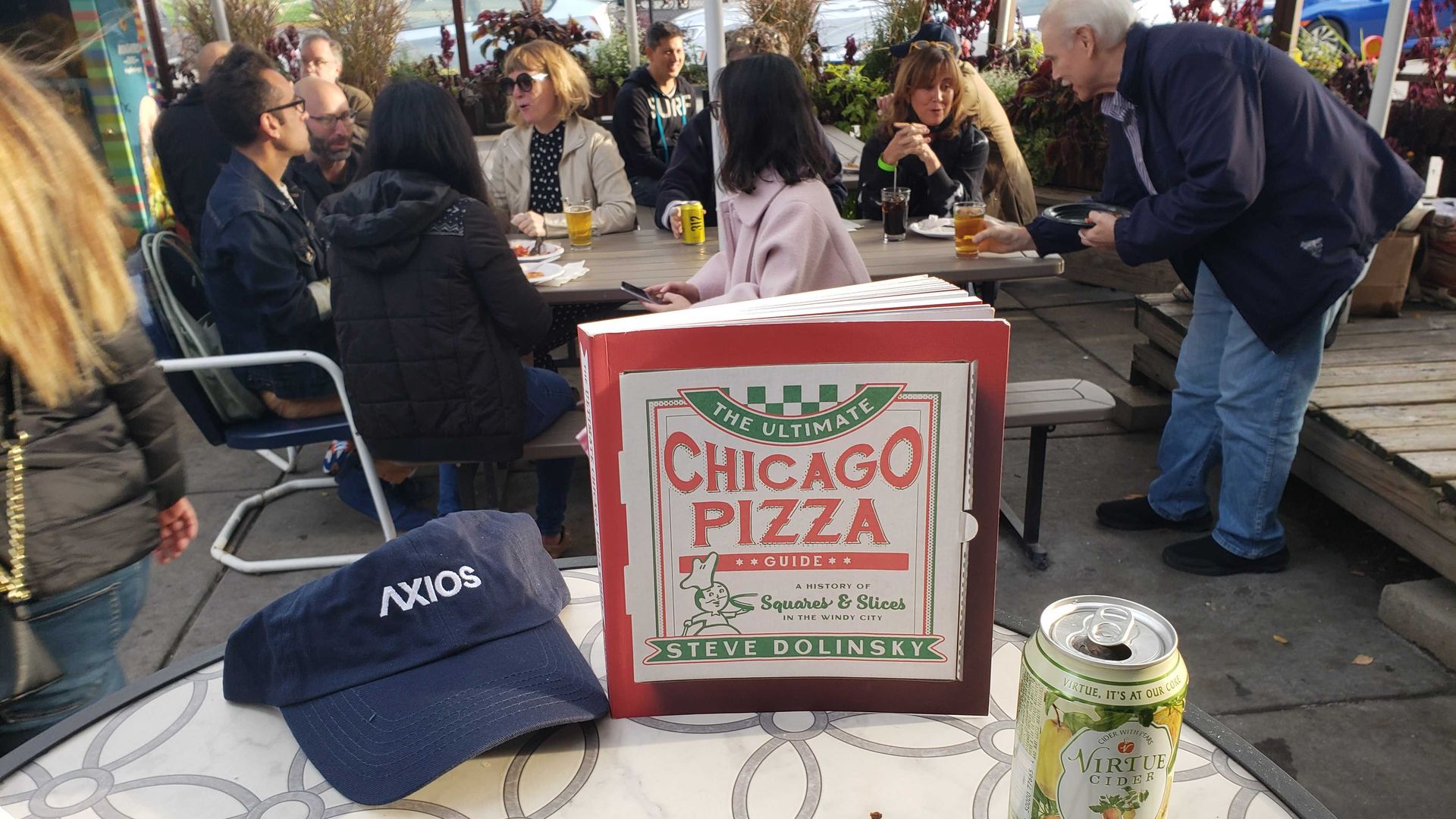 A hat, book and can and people behind. 