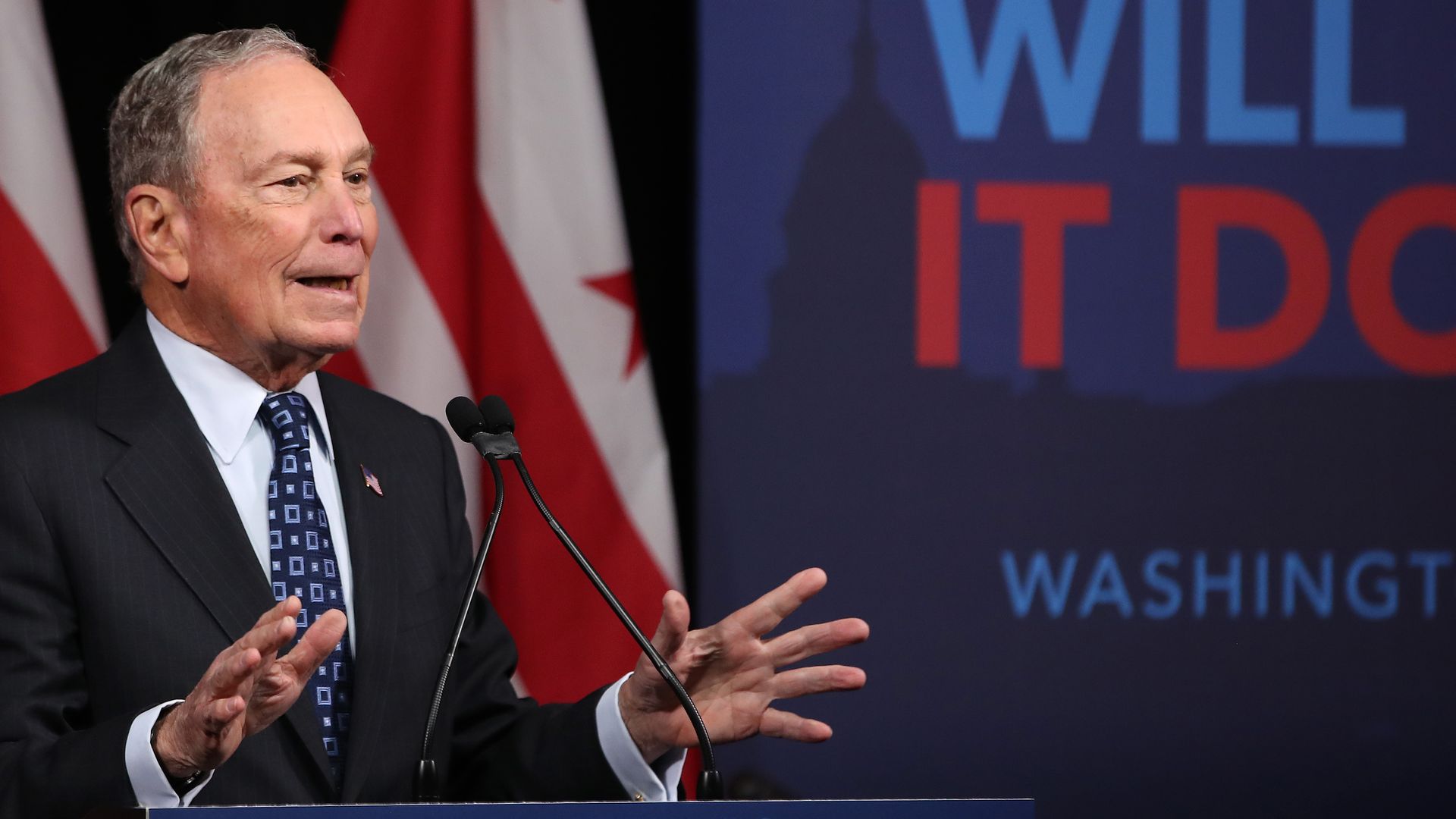 In this image, Bloomberg stands and speaks at a podium while campaign for the 2020 election