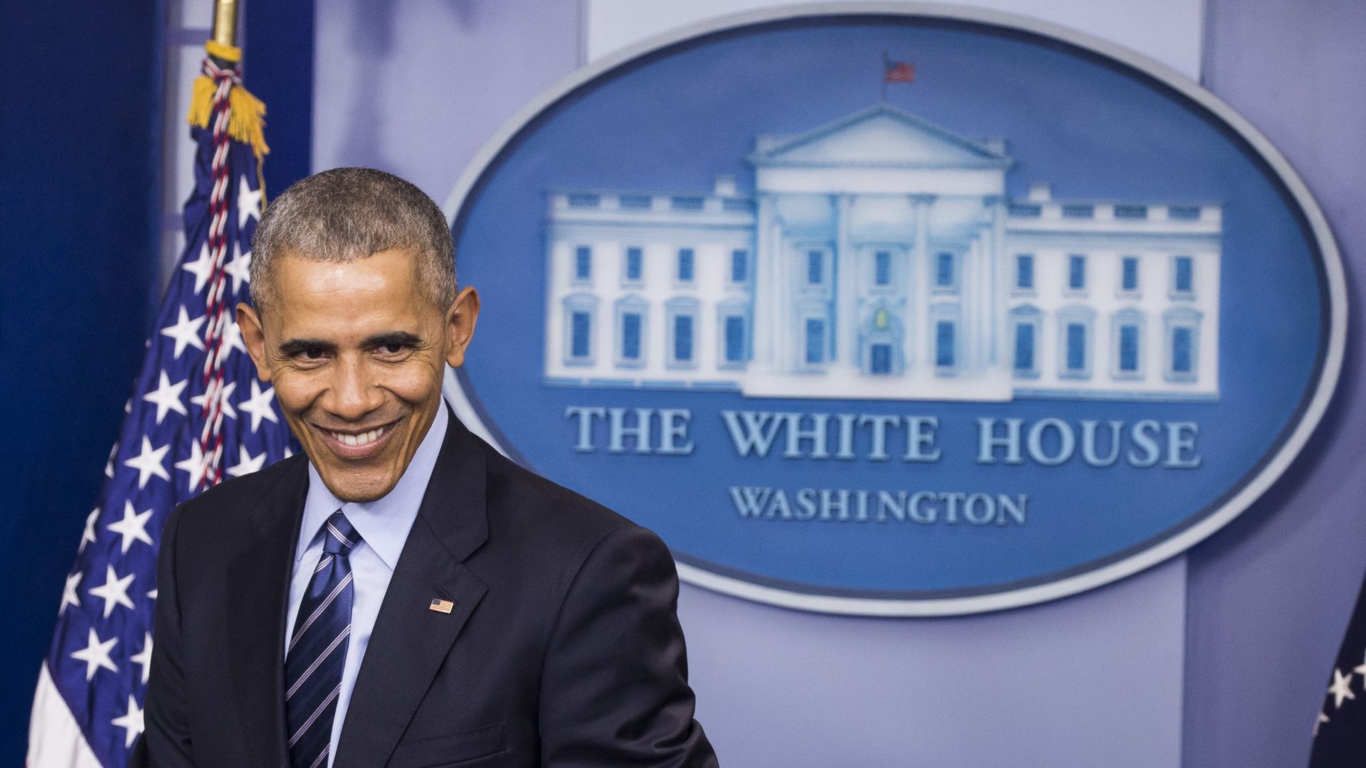Then-President Obama, smiling, in the White House briefing room.