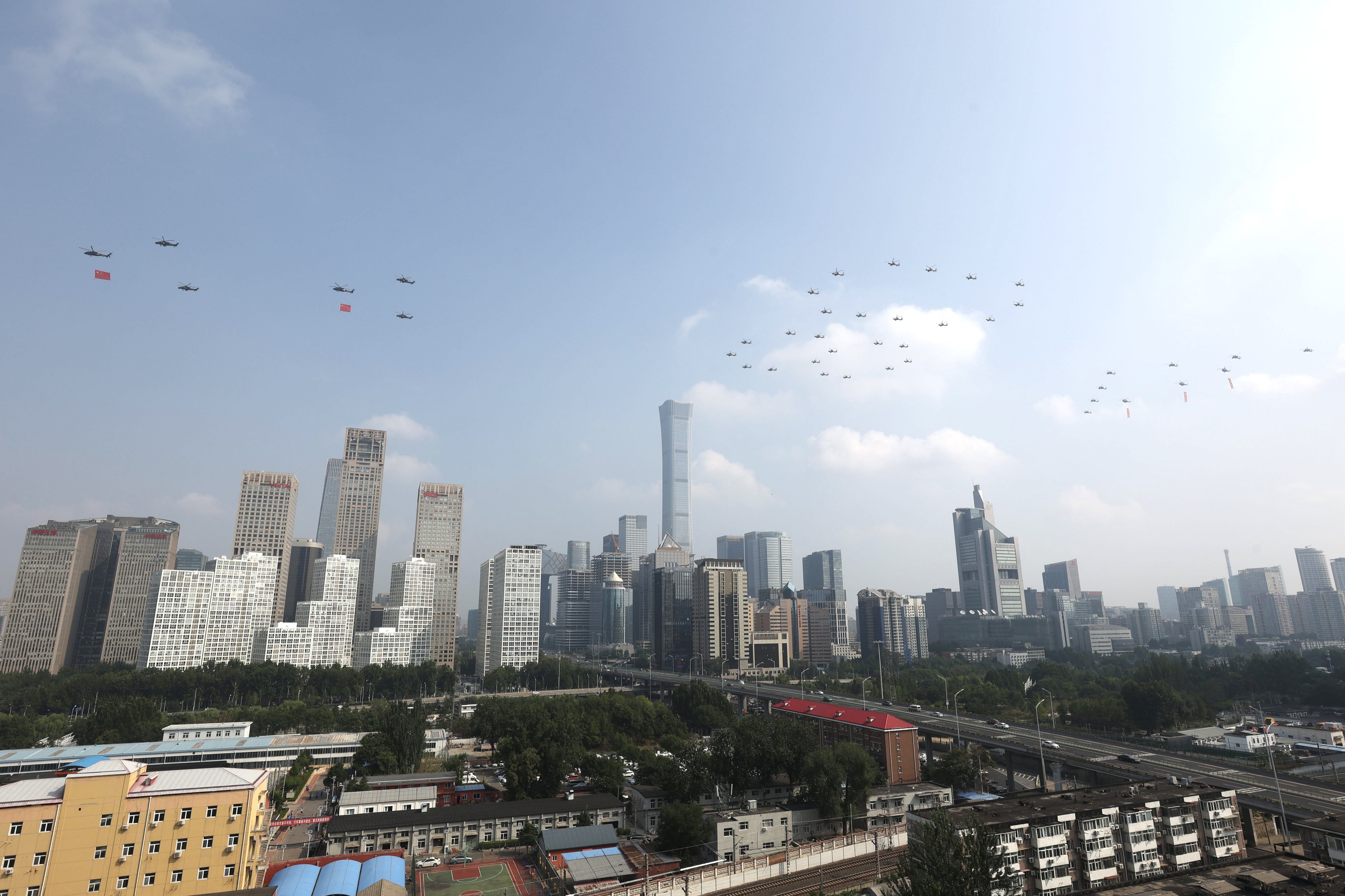 The flag-guarding air echelon flies over Tiananmen Square and the Beijing skyline that features a variety of sky scrapers during a grand Chinese military parade.