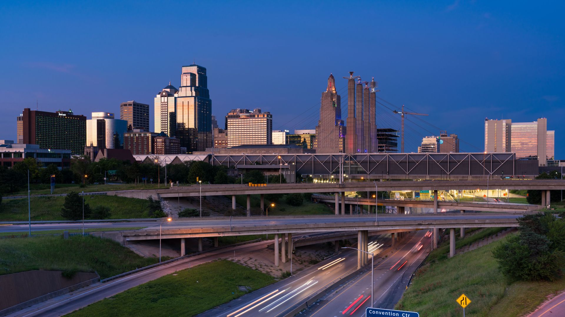 Photo shows the Kansas City skyline at twilight with interstates crisscrossing in the foreground.