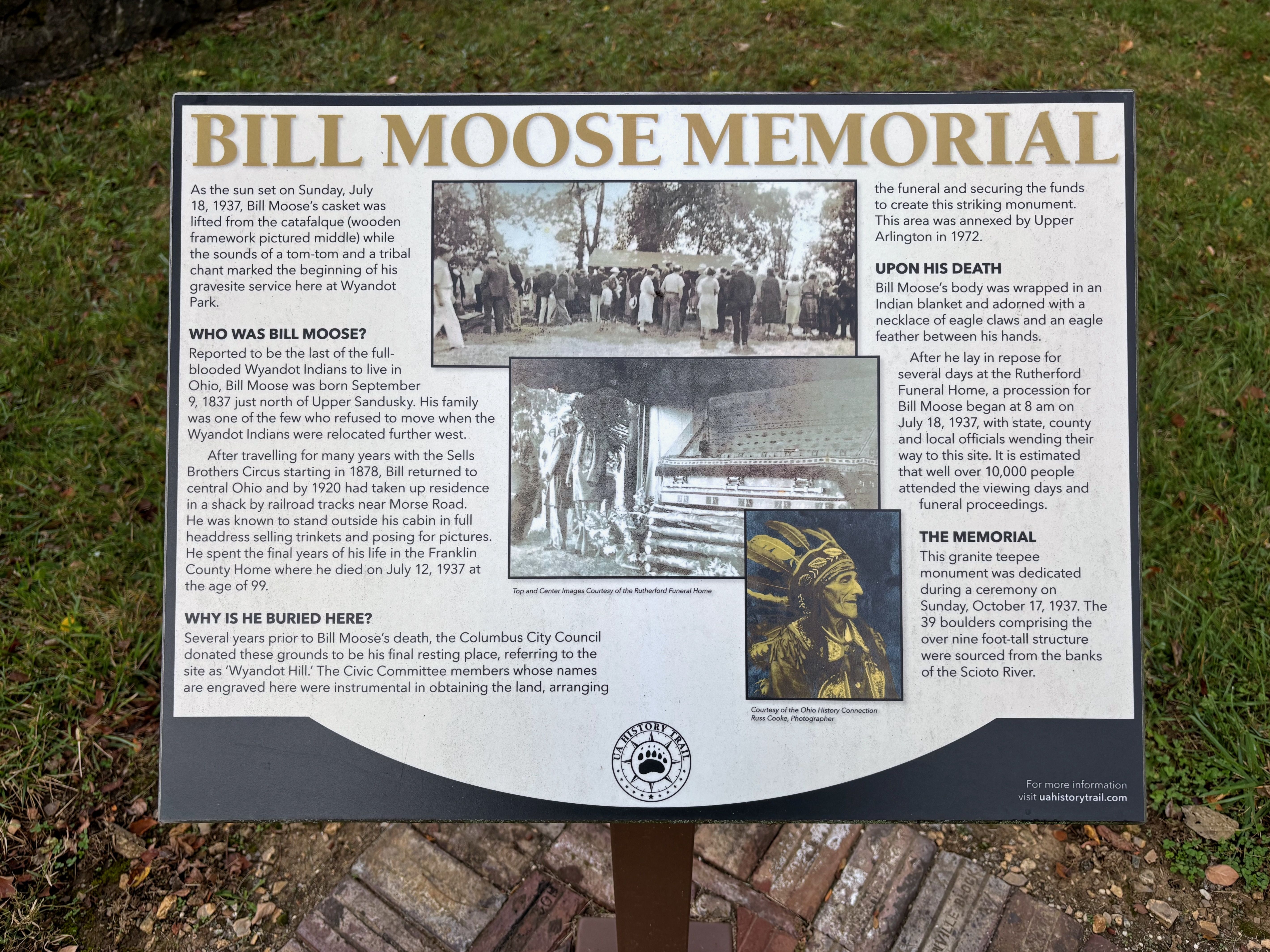 Informational sign titled "Bill Moose Memorial" with historical photos and text about Bill Moose of the Wyandot tribe, his death in 1937, and the memorial monument in Upper Arlington.