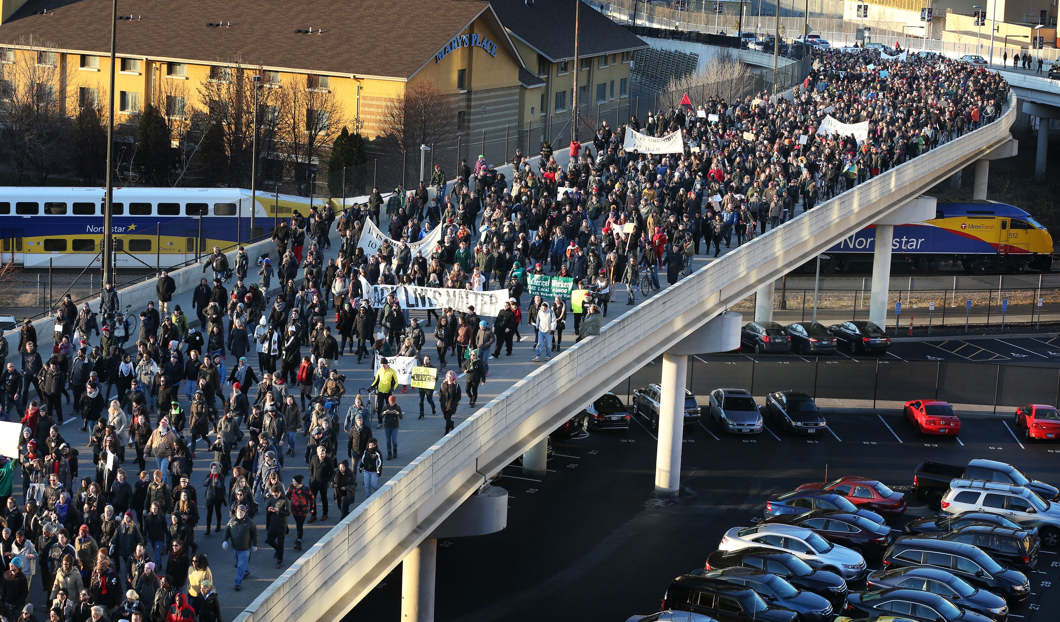 Düzinelerce protestocu bir otoyolu geçiyor.