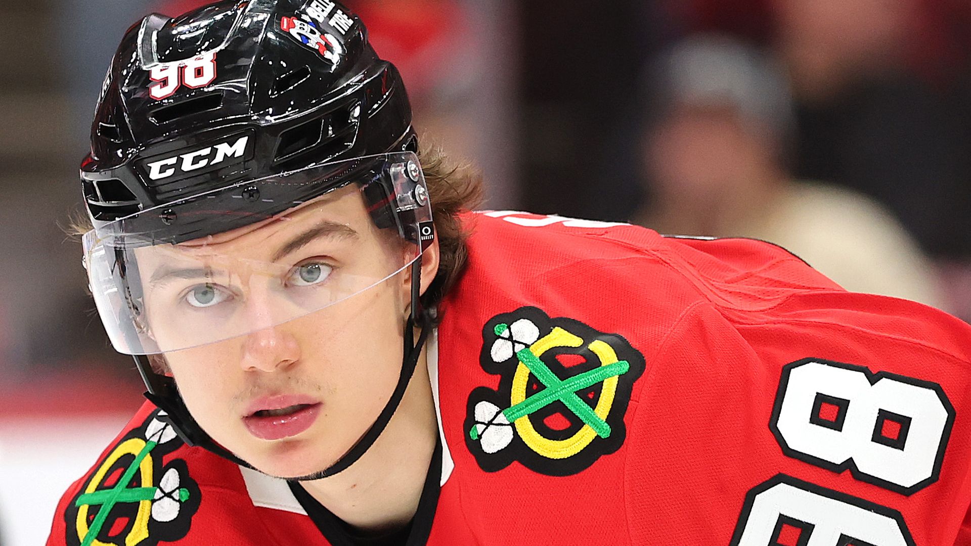 Photo of a hockey player on the ice, wearing helmet and a jersey.