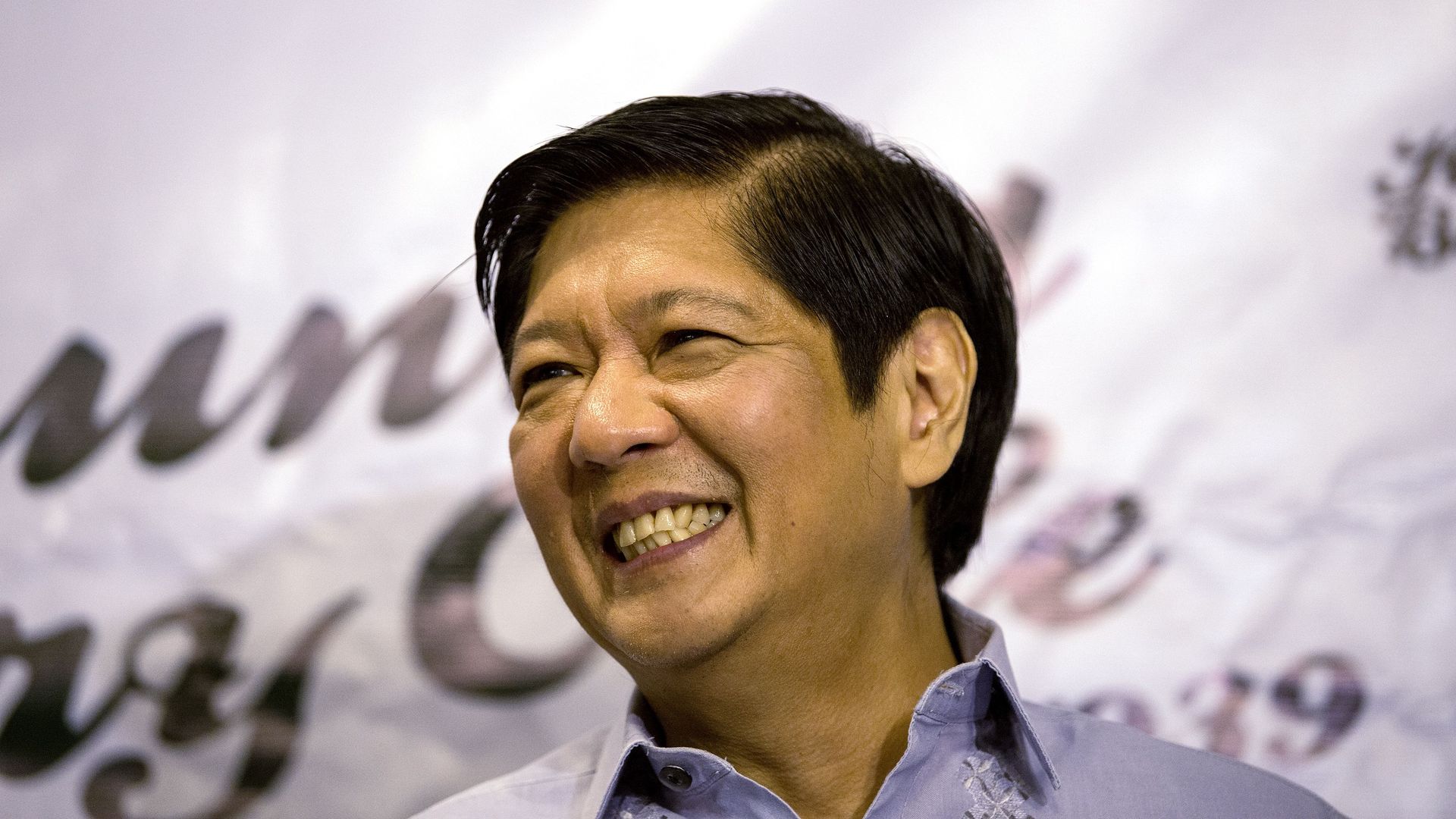 Headshot of man smiling and looking beyond the camera. Campaign canvas in the background. 