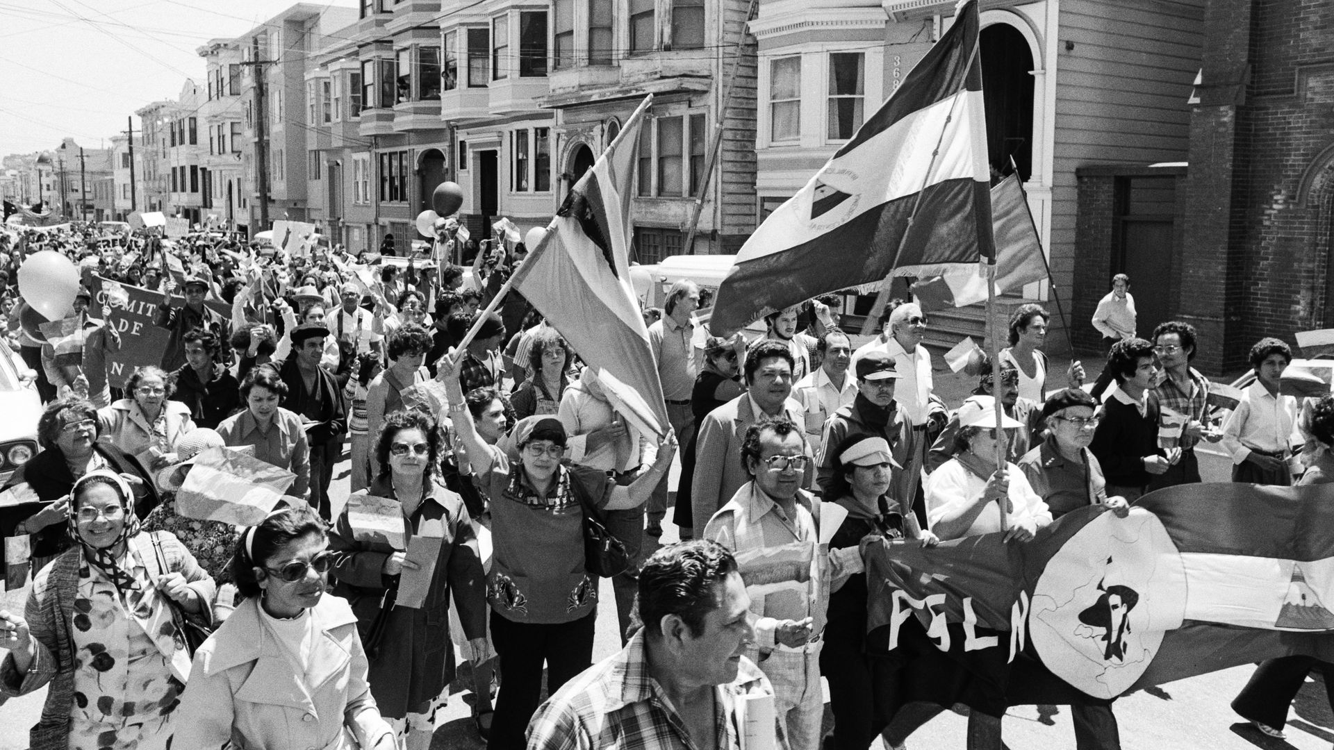 Photo showing a crowd of people marching down the street with Nicaraguan flags, banners and balloons