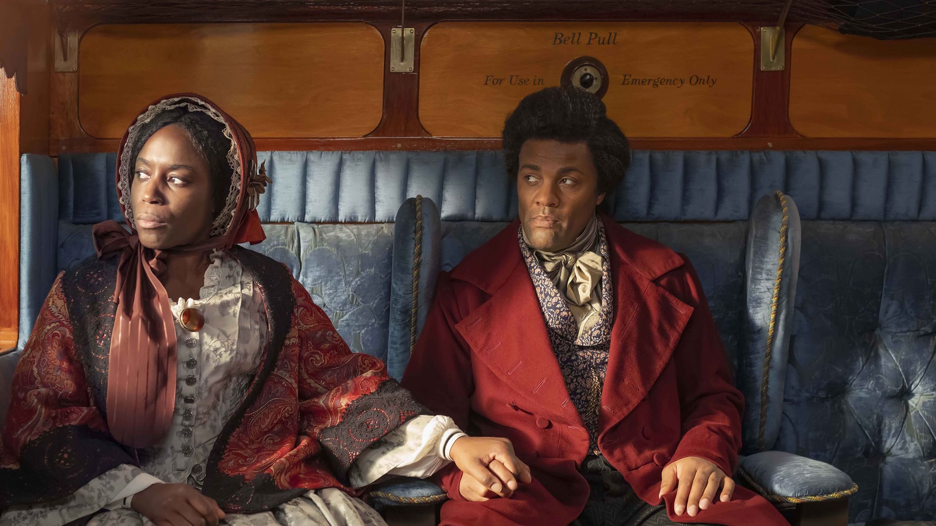 2 actors sit in a carriage dressed in 19th century clothes 