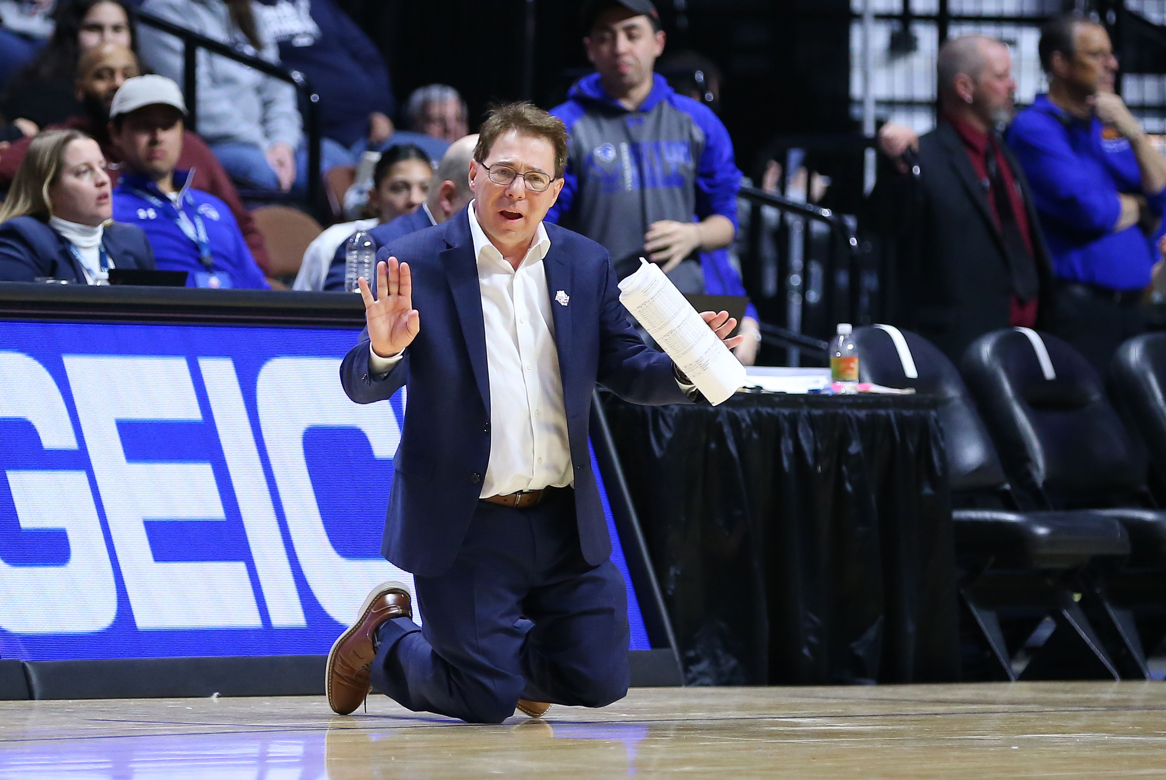 Photo of a coach on his knees on the sidelines of a basketball game