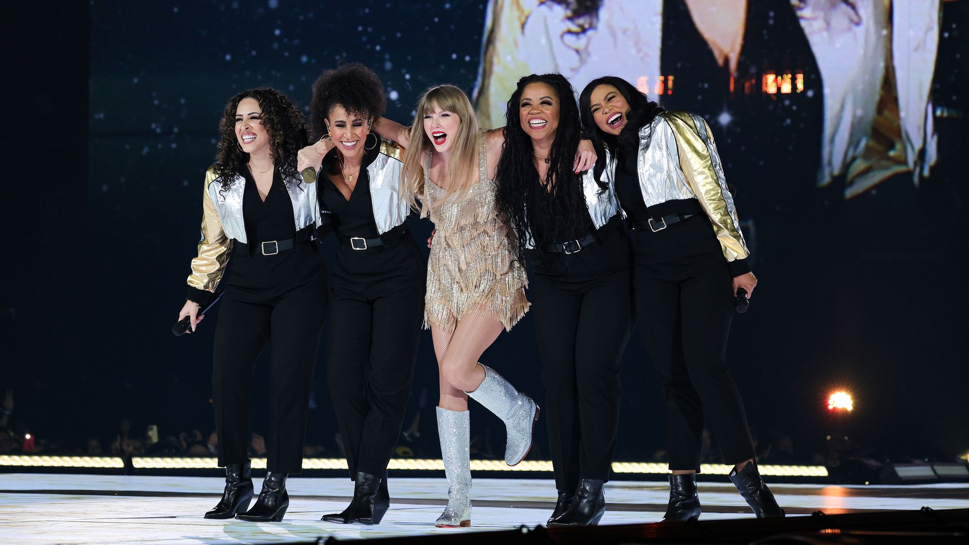 Taylor Swift with four dancers on each side of her on stage. 