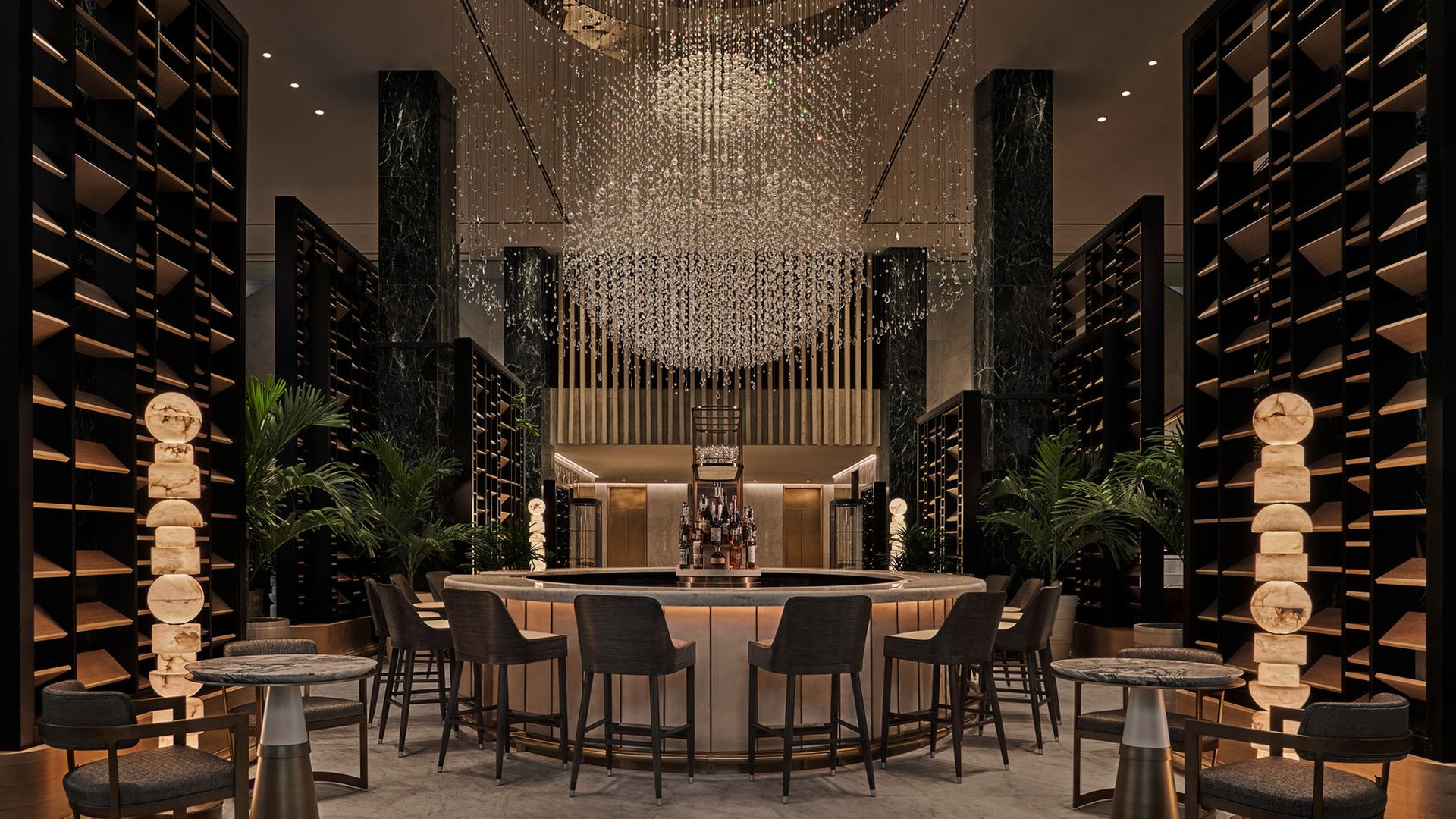 image of a circular bar with 6 seats around it and a stunning chandelier overhead at the Chandelier Bar in New Orleans