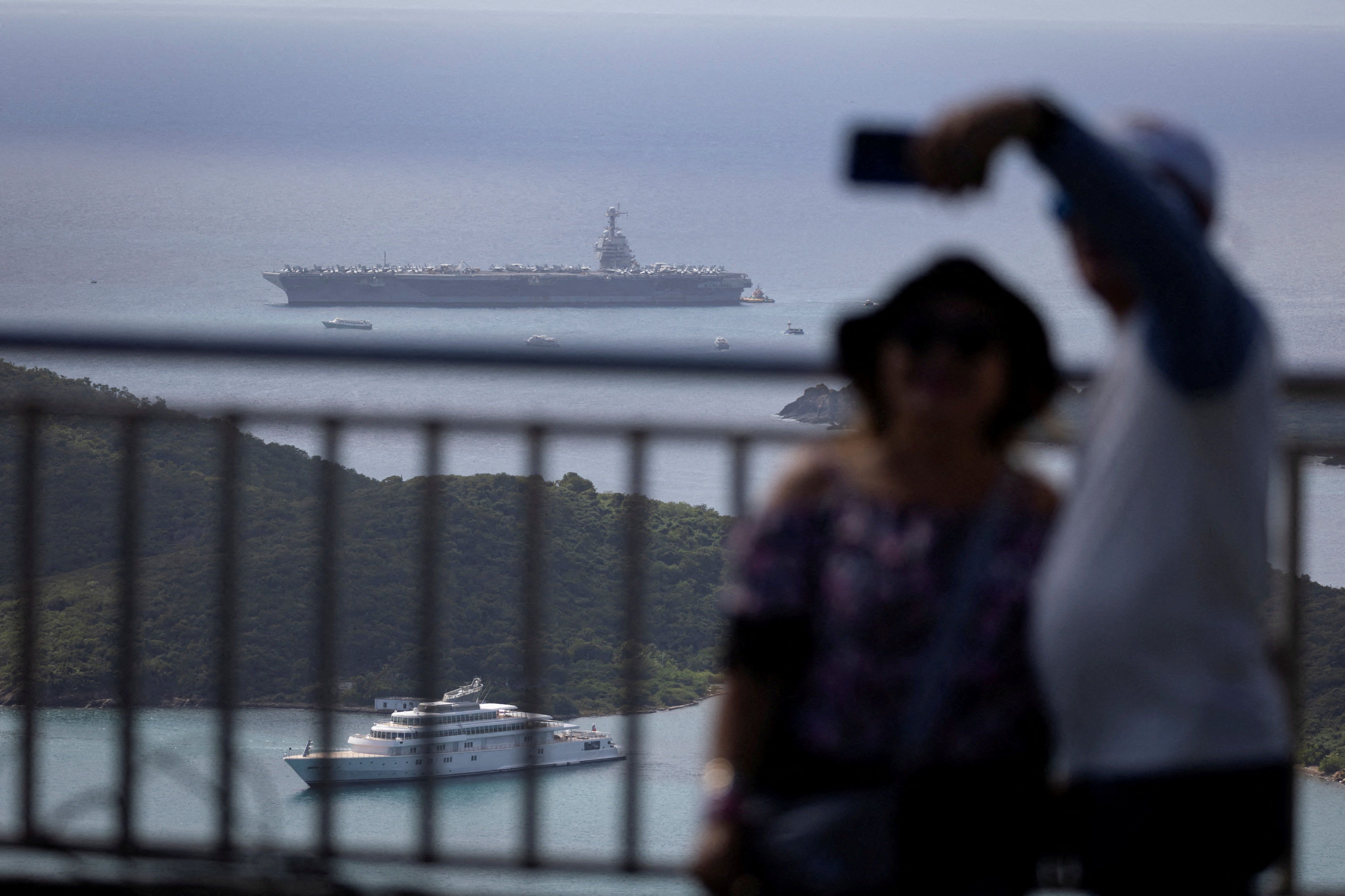 Tourists pose for a selfie yesterday with the USS Gerald R. Ford in the background in Saint Thomas, U.S. Virgin Islands.