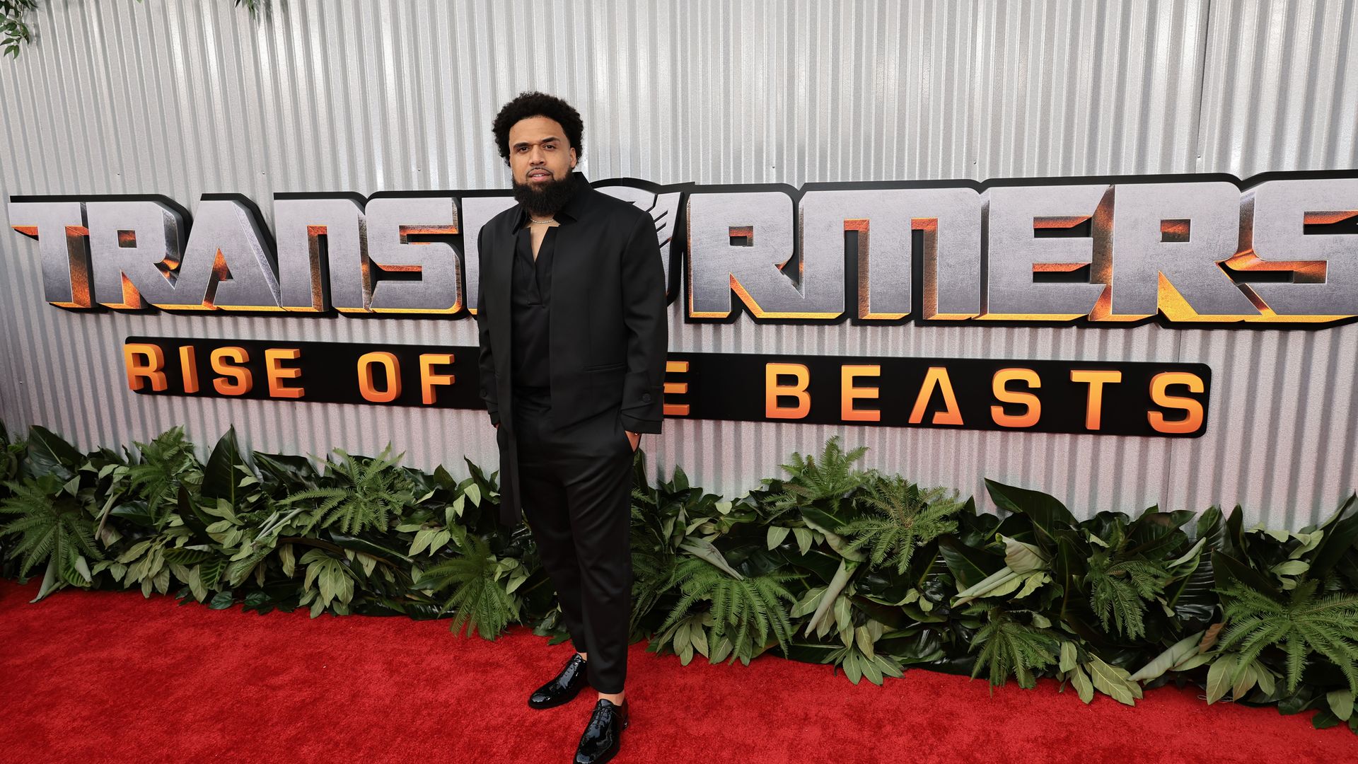 Man stands on red carpet for "Transformers: Rise of the Beasts" premiere. 