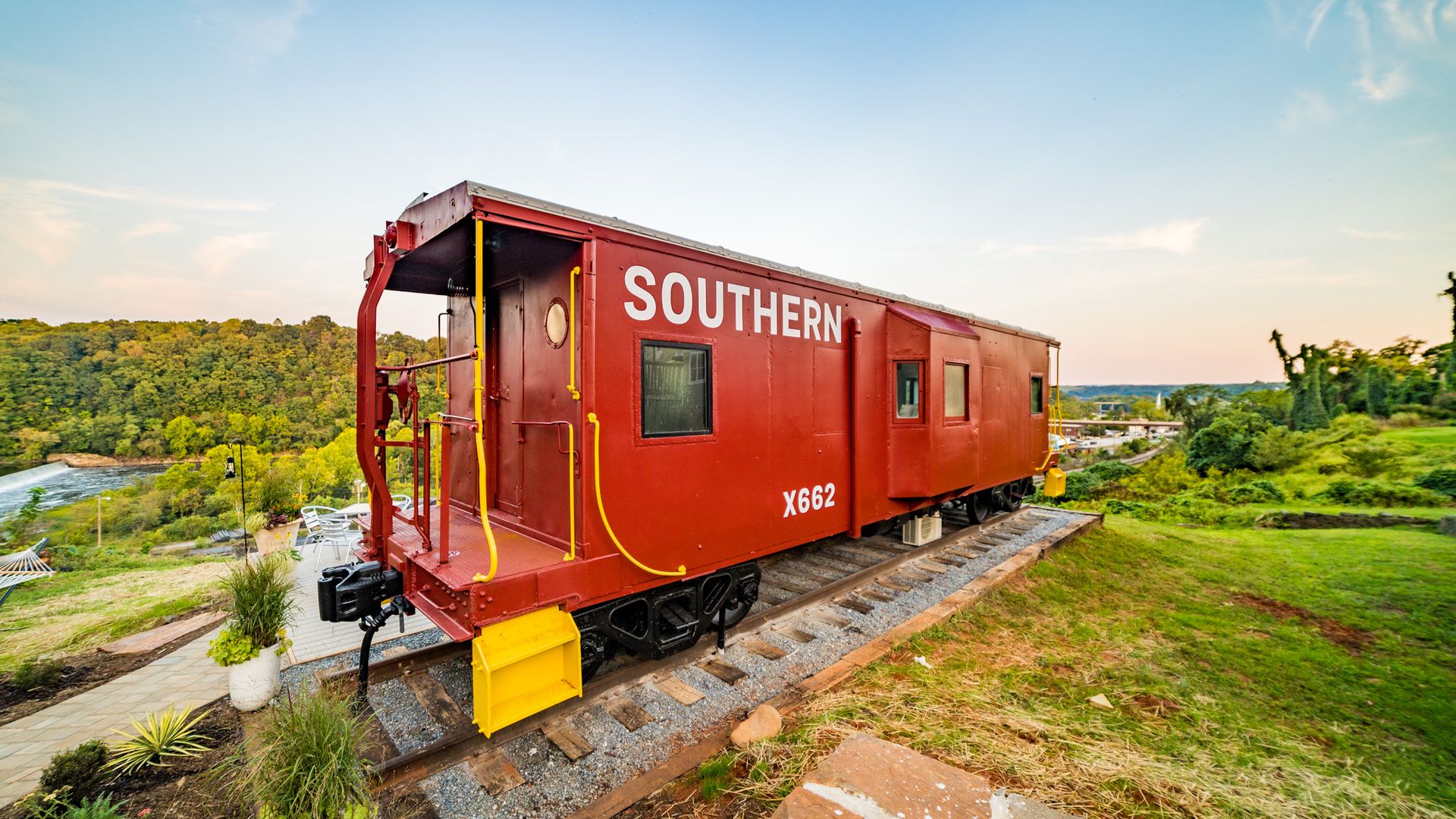 red train caboose on makeshift train tracks surrounded by greenery