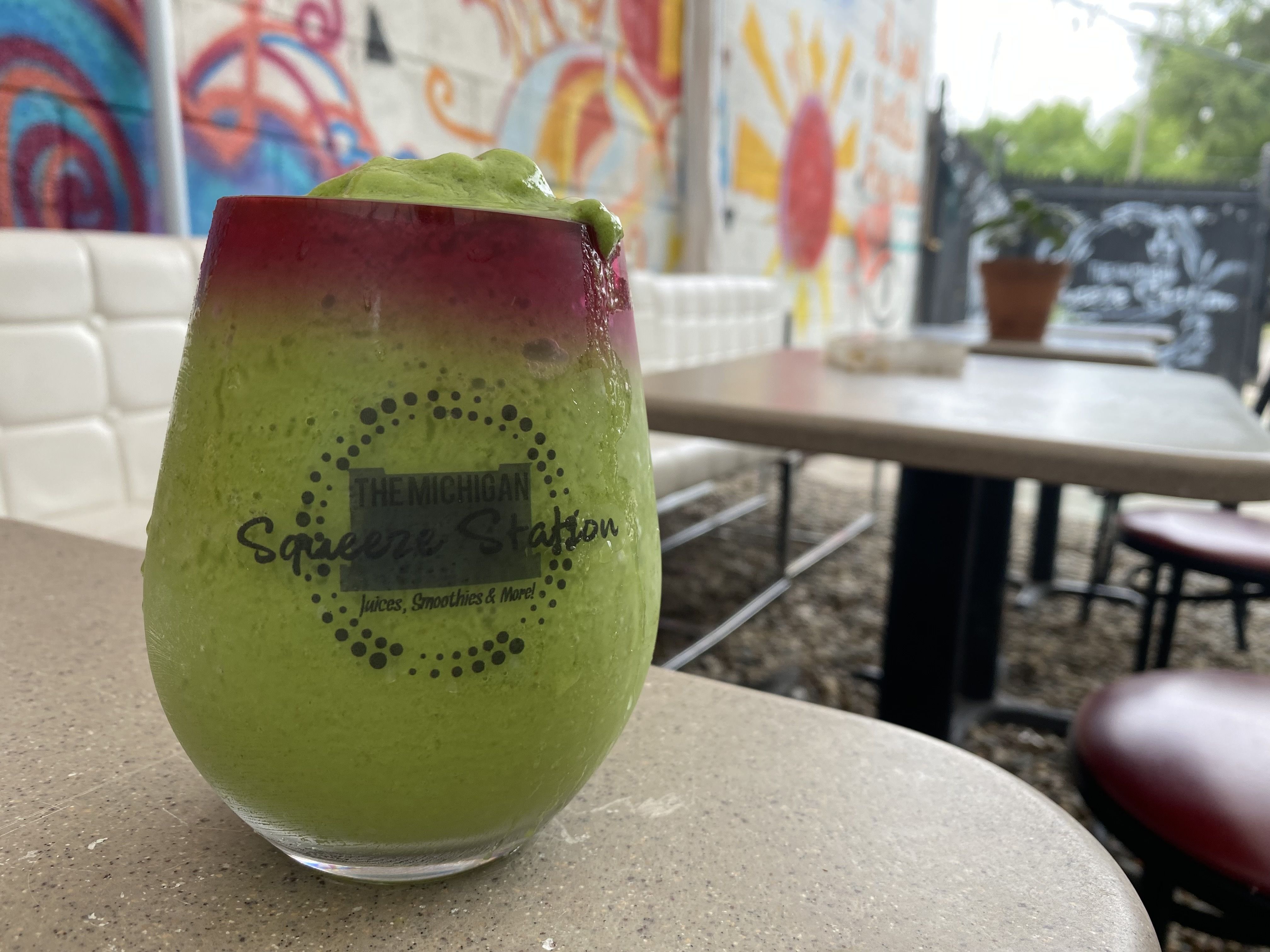 A smoothie in a glass labeled "Michigan Squeeze Station" is pictured in front of graffiti.