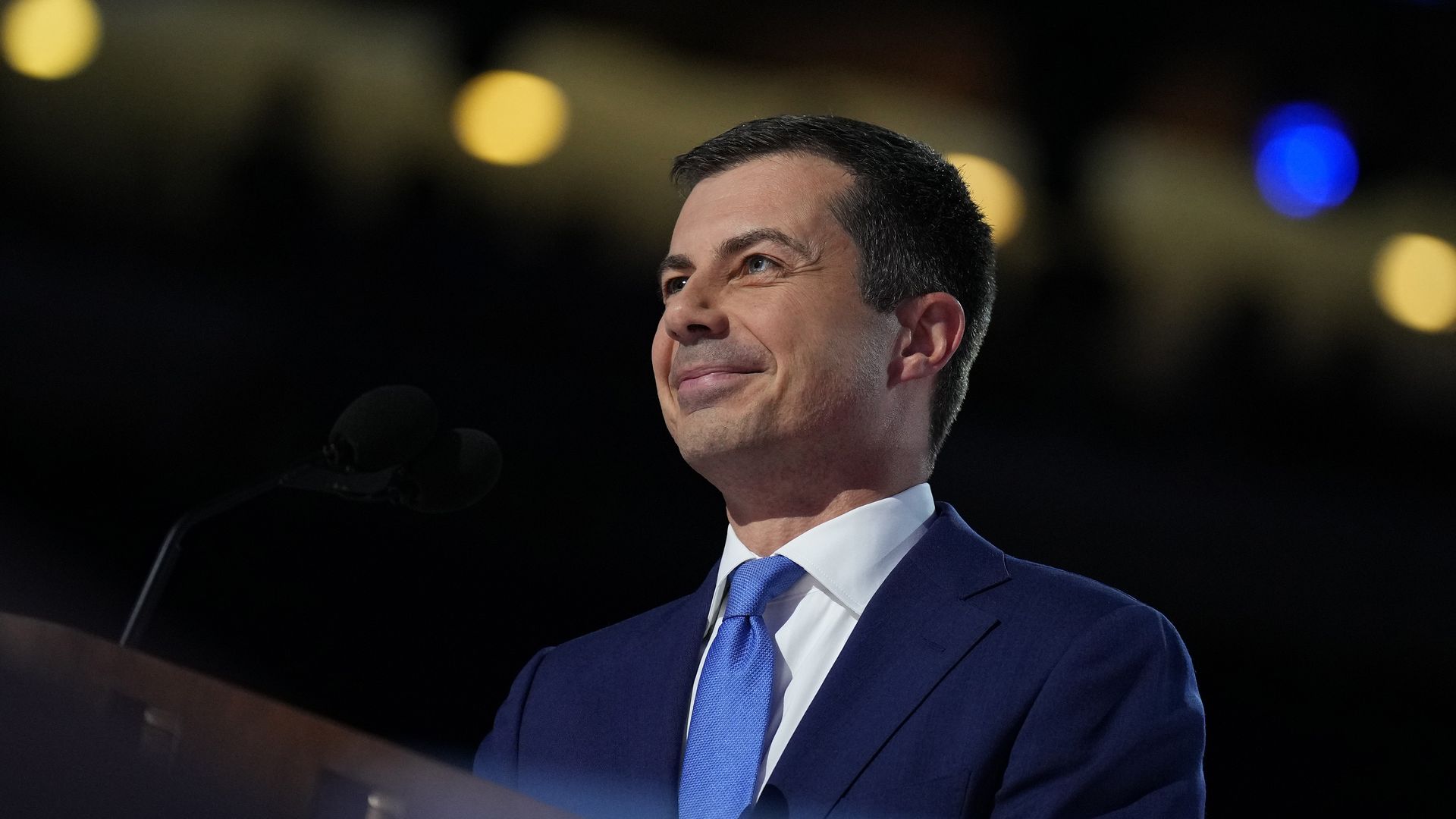 Buttigieg photographed wearing a dark suit, white shirt and blue tie
